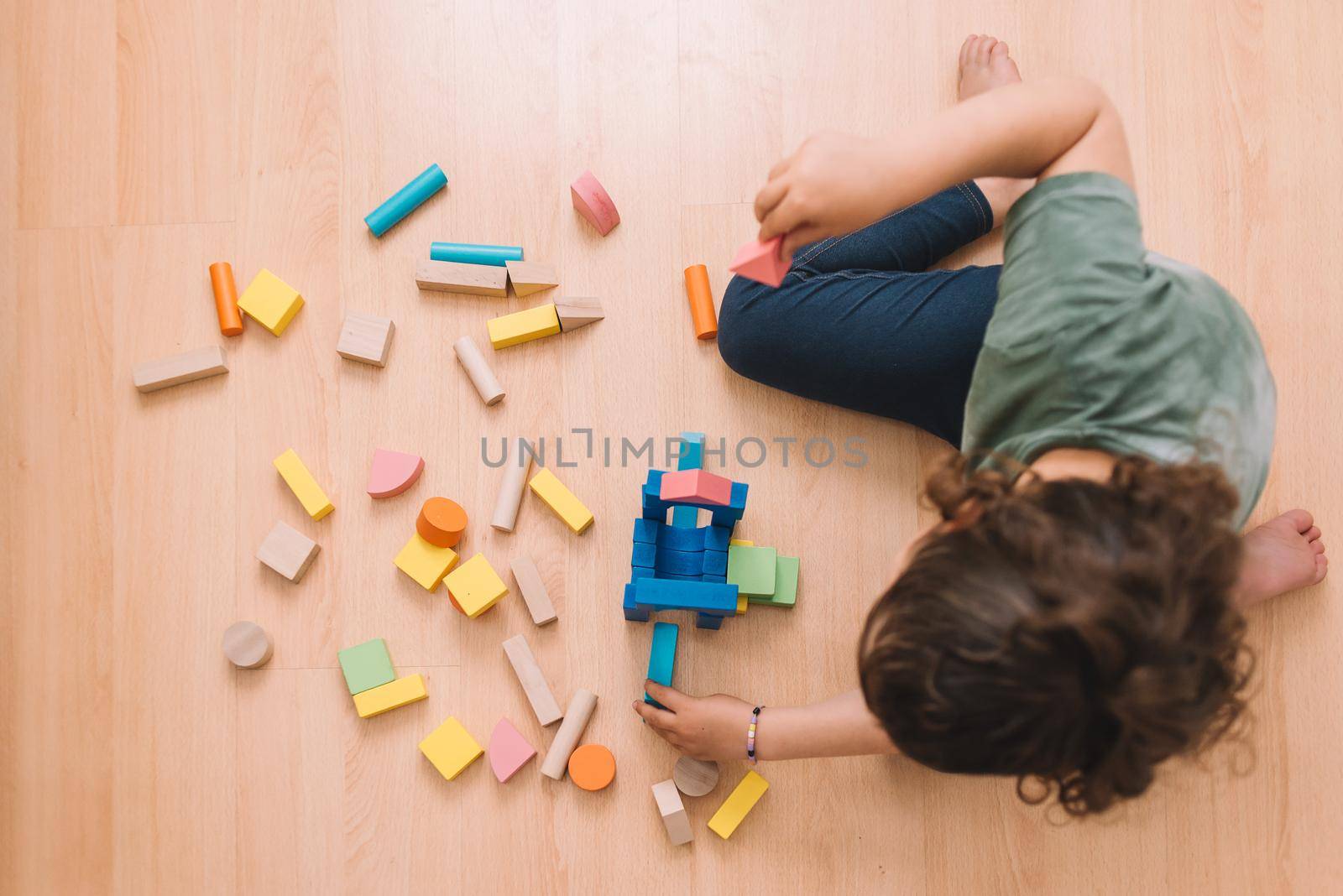 girl playing on the floor with building blocks by raulmelldo