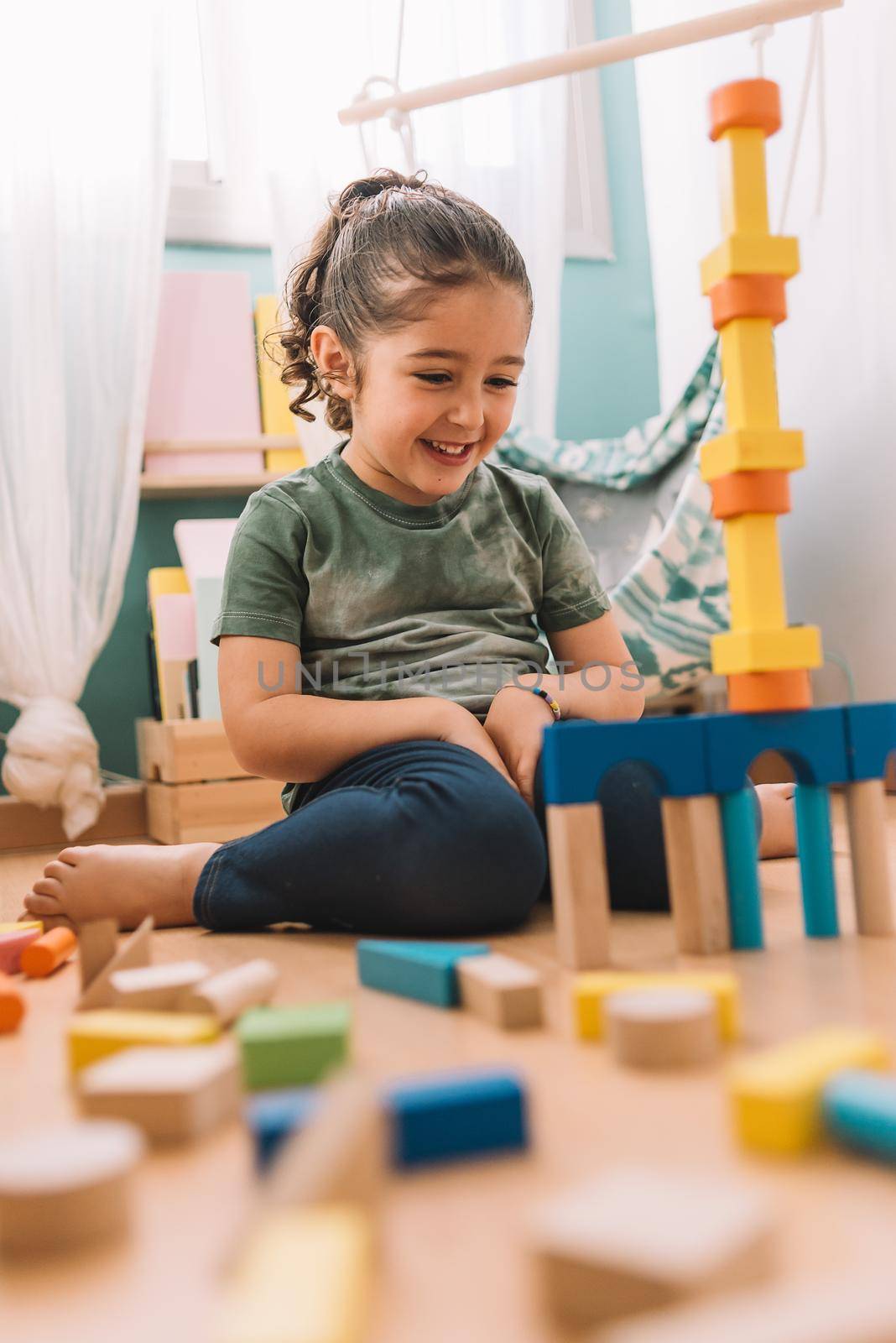 happy girl building with colorful wooden blocks by raulmelldo