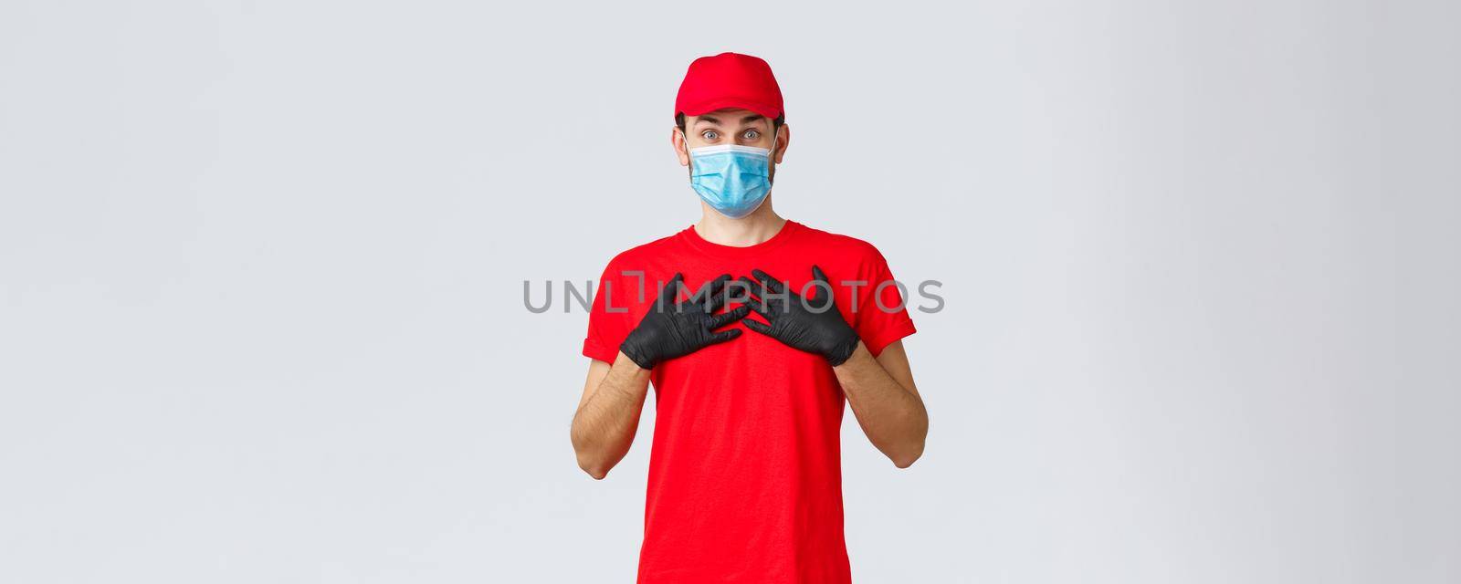 Covid-19, self-quarantine, online shopping and shipping concept. Is it for me, touched and surprised delivery guy receive gift or compliment, press hands chest flattered, wear face mask and gloves.