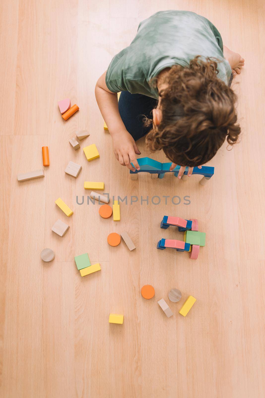 top view of a little girl playing in the floor with colorful wooden building block toys at home or kindergarten, educational toys for creative children