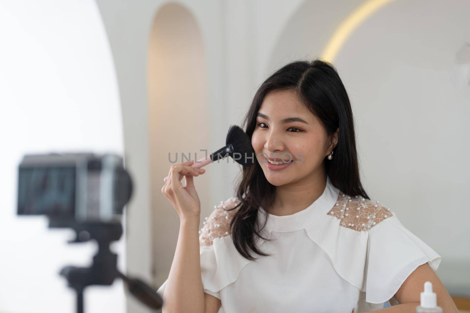 Famous blogger. Cheerful female vlogger is showing cosmetics products while recording video and giving advices for her beauty blog. by nateemee