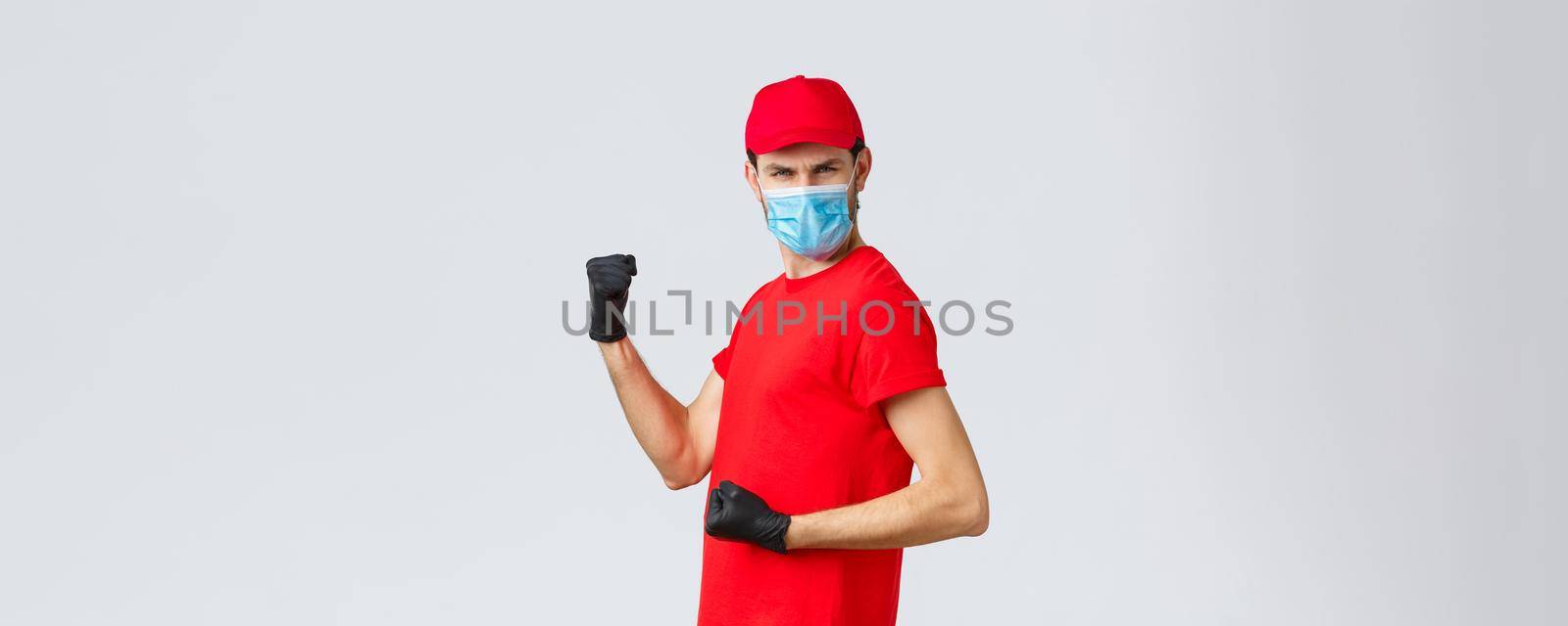 Covid-19, self-quarantine, online shopping and shipping concept. Energized, excited delivery guy do champion dance, fist pump and looking empowered, celebrate success, rejoicing in courier outfit by Benzoix