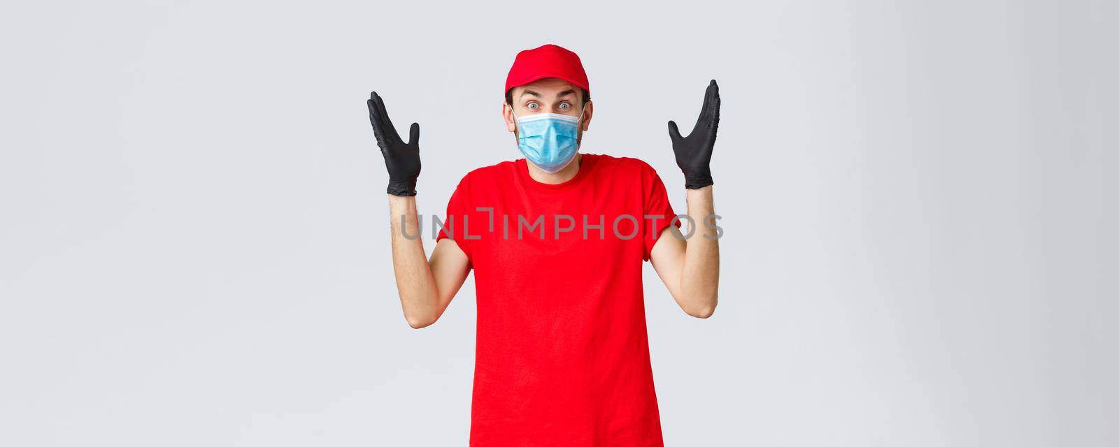 Covid-19, self-quarantine, online shopping and shipping concept. Surprised and confused delivery guy in medical mask, gloves and re duniform, shrugging, cant understand how it happened.