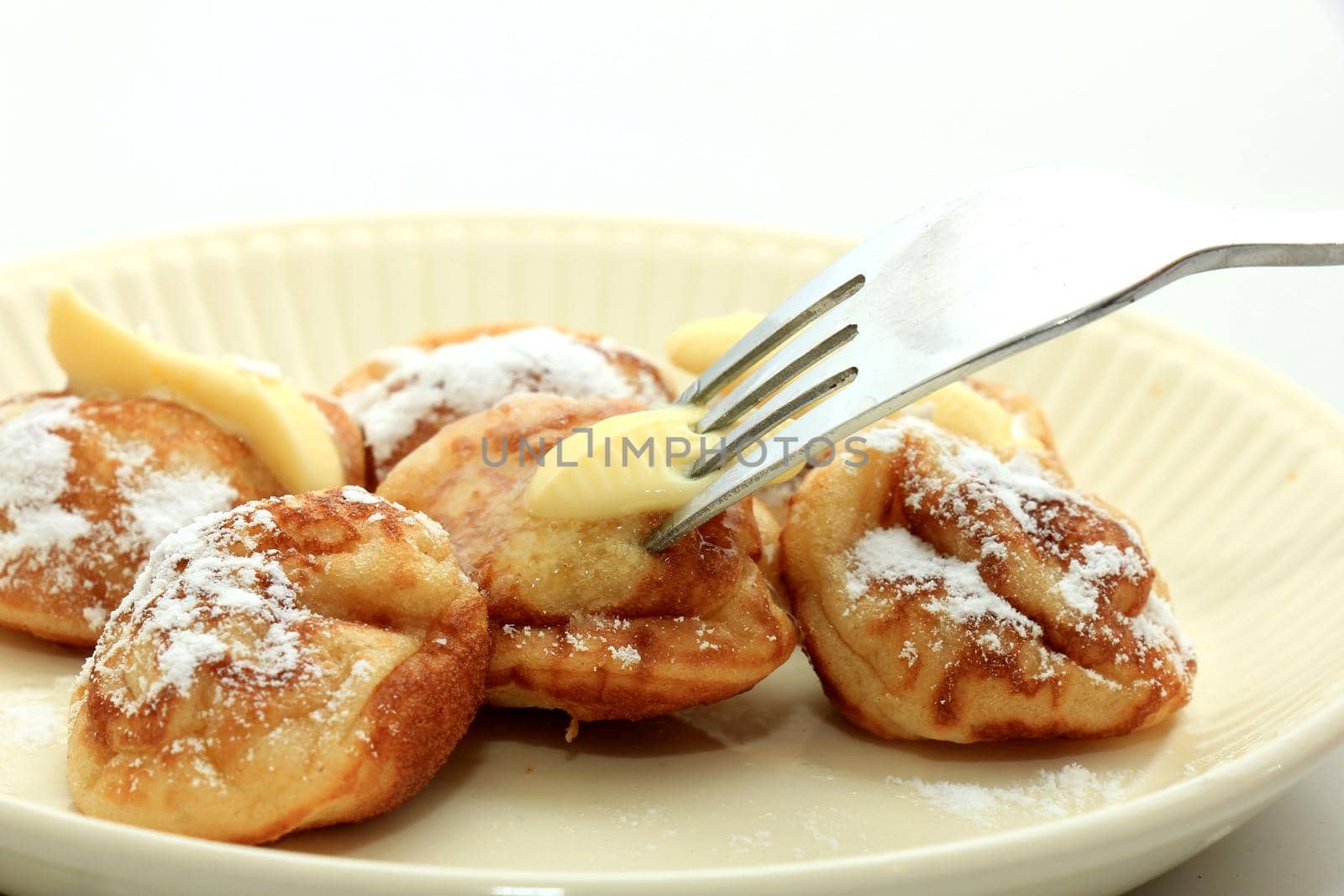 Poffertjes, Dutch small, fluffy pancakes, served with powdered sugar and butter.