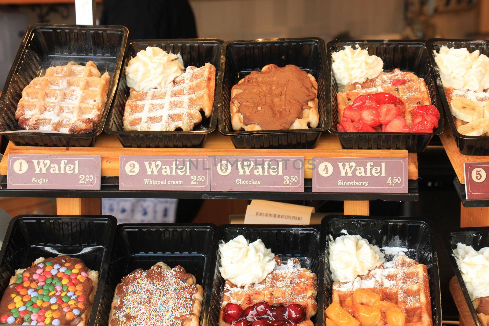 Fresh made Belgium waffles with various fruit toppings and cream (tags: product and price information in English and Dutch.