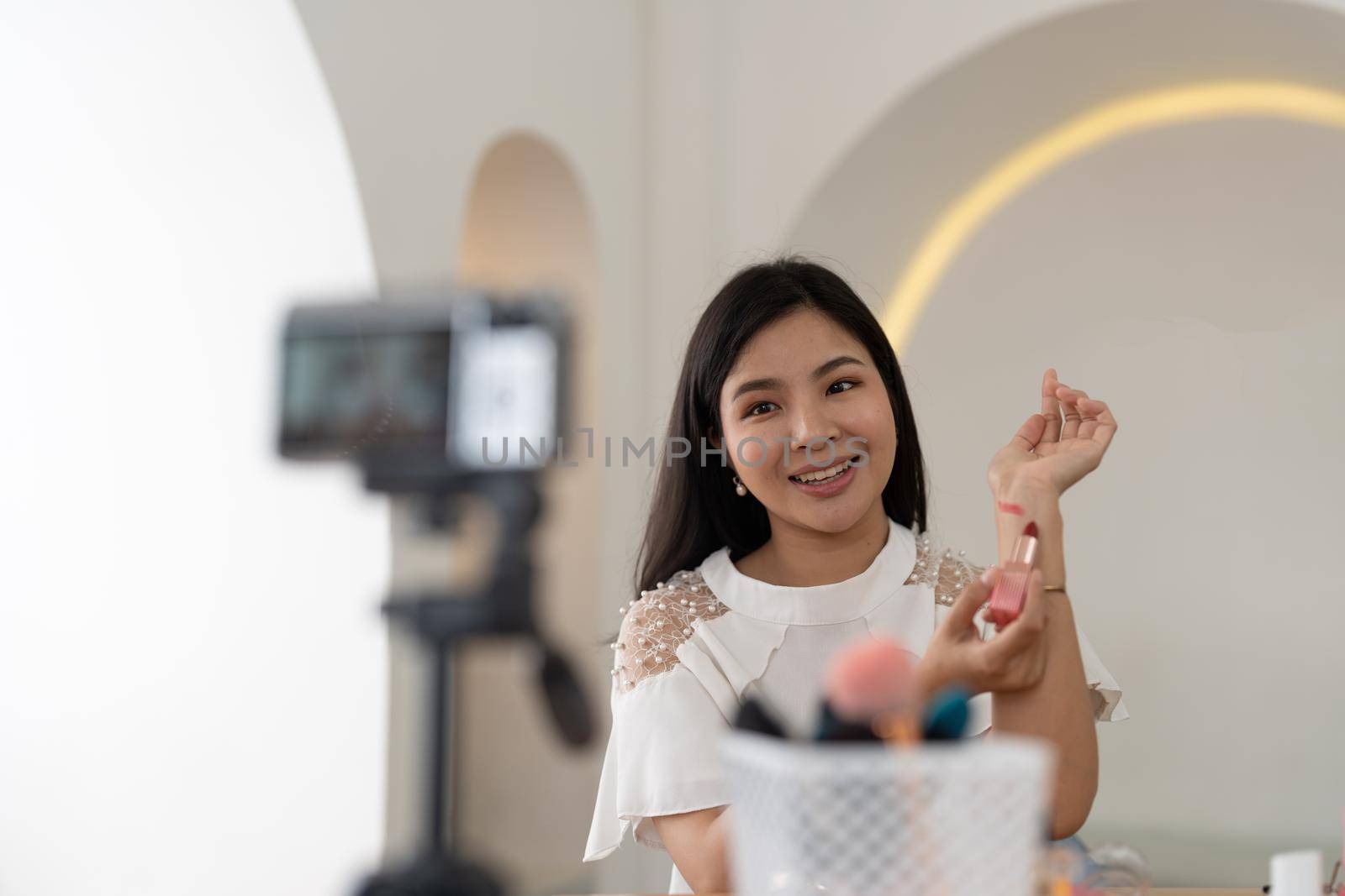 Asian young female blogger recording vlog video with makeup cosmetic at home online influencer on social media concept.live streaming viral by nateemee