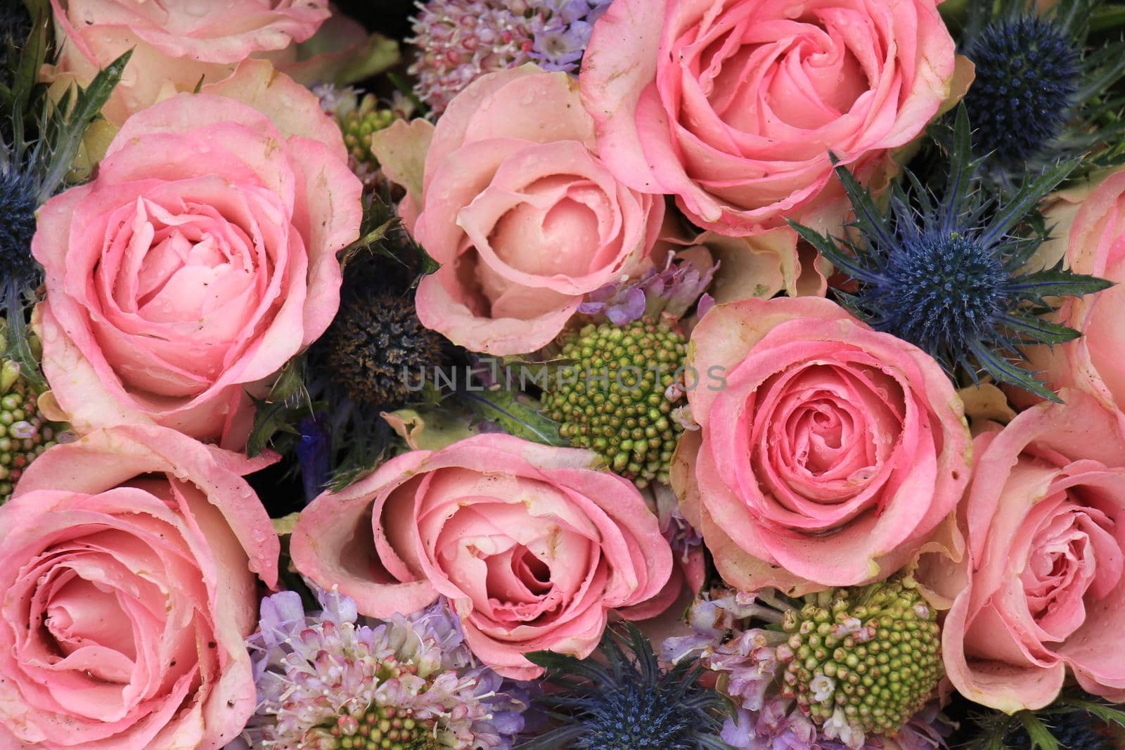 Pink roses and blue sea holly in a wedding flower arrangement by studioportosabbia