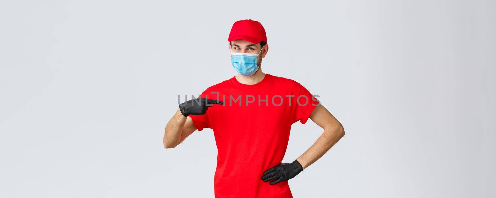 Covid-19, self-quarantine, online shopping concept. Confident smiling delivery guy in face mask, gloves in uniform, pointing himself. Courier provide fast shipping during coronavirus outbreak.