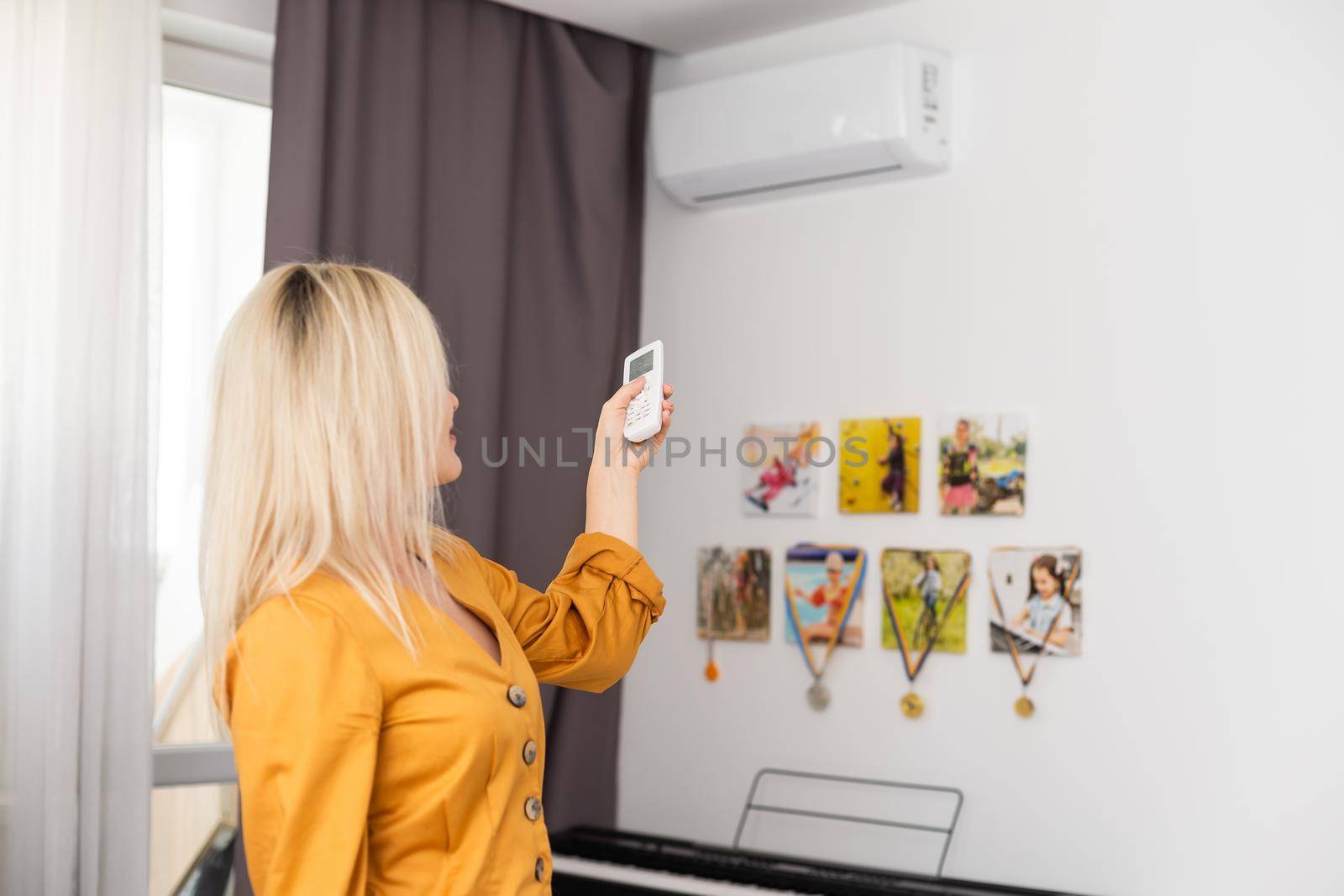 Woman holding remote control aimed at the air conditioner.