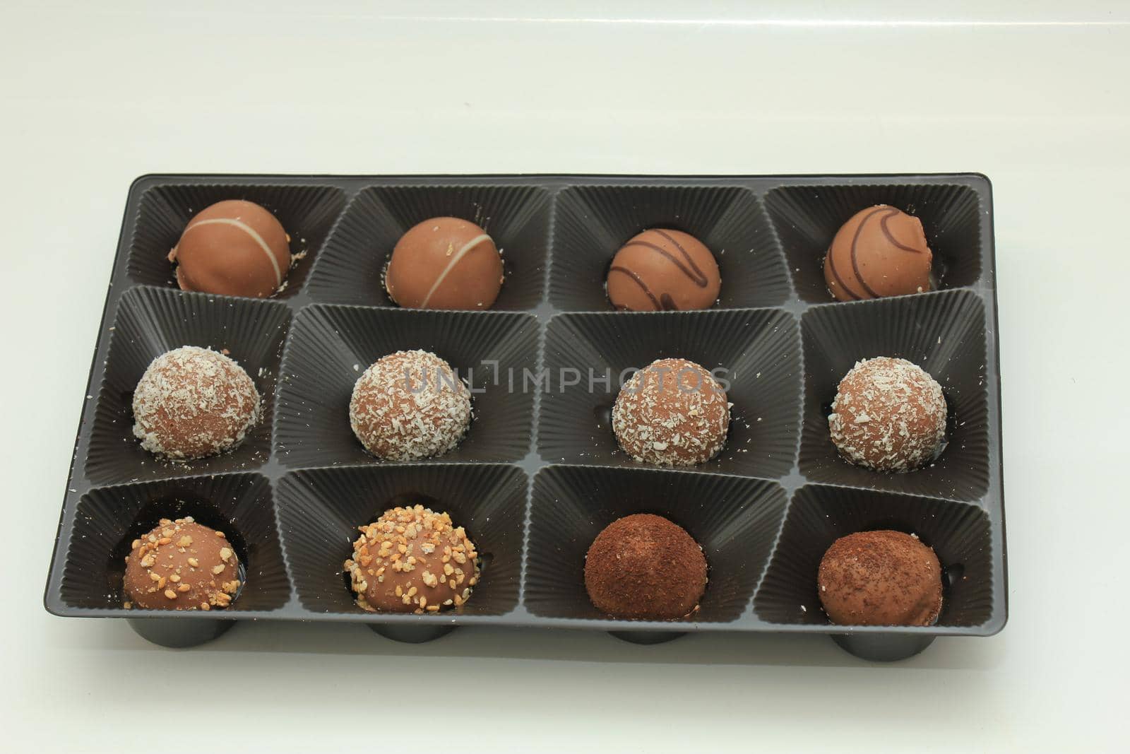 Various chocolates in a tray, bonbons with different topping and filling