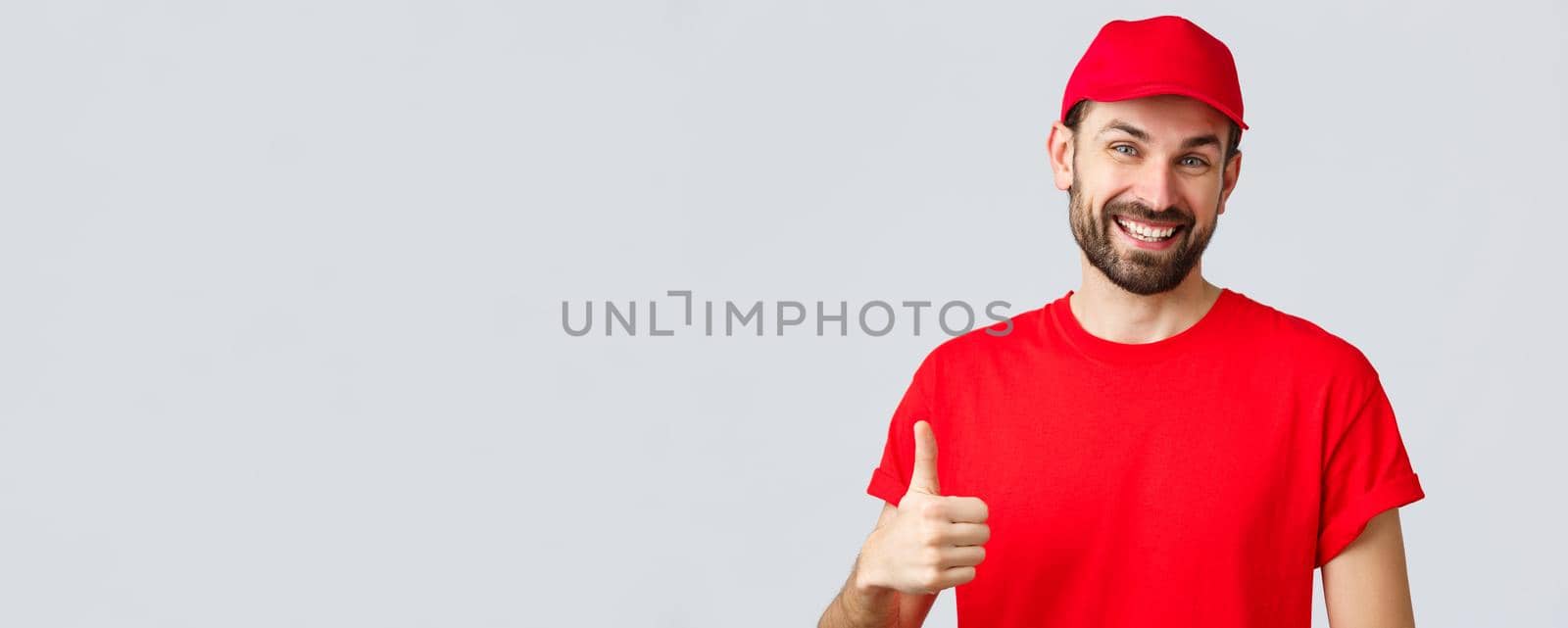 Online shopping, delivery during quarantine and takeaway concept. Friendly, cheerful courier in red cap and t-shirt uniform, encourage make internet orders, thumb-up in approval or recommendation by Benzoix