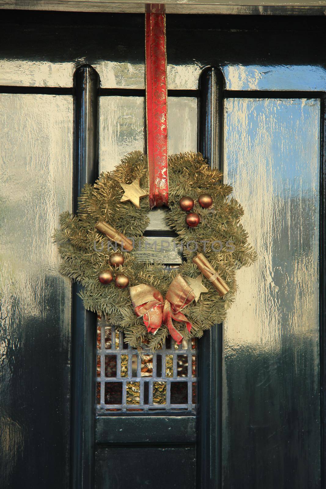 Classic christmas wreath with decorations on a door by studioportosabbia