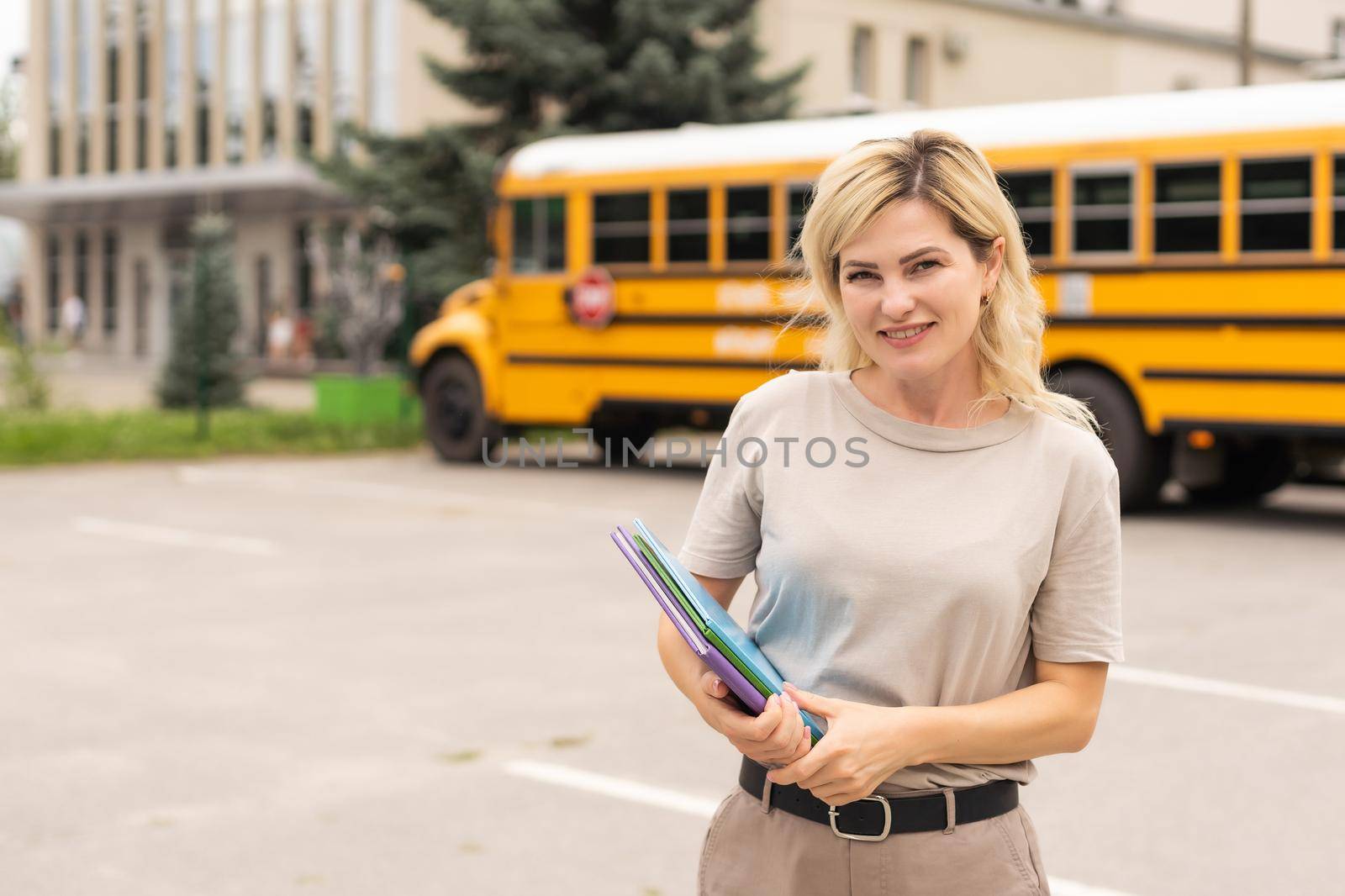 Portrait of positive middle aged woman teacher, psychologist, mentor, therapist, counselor near the school bus.