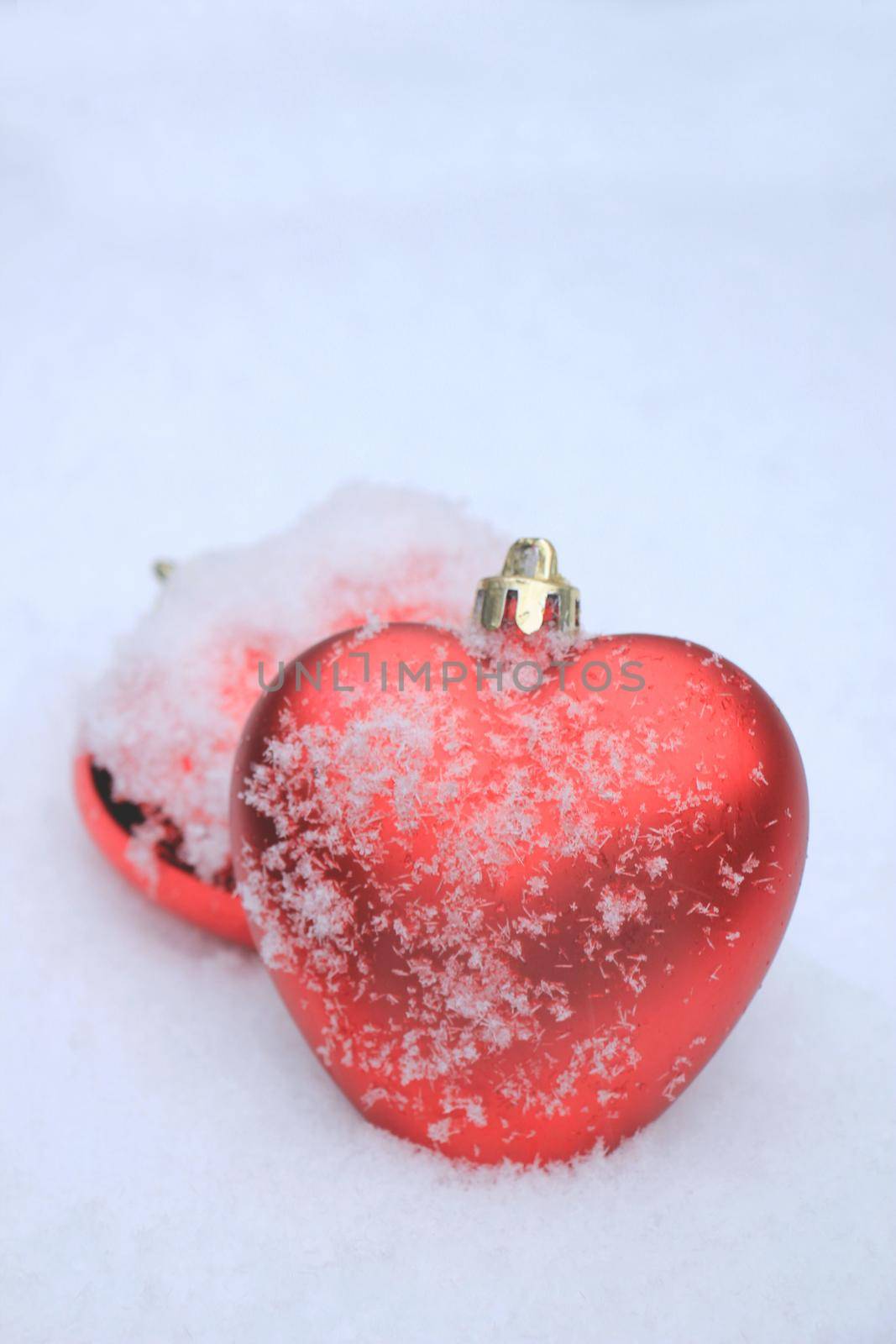 Red heart shaped ornament in fresh fallen snow by studioportosabbia