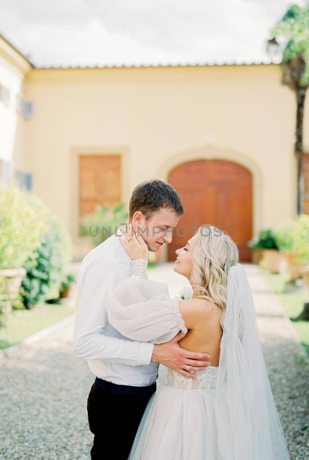 Bride and groom hugging in front of a building in the garden. High quality photo