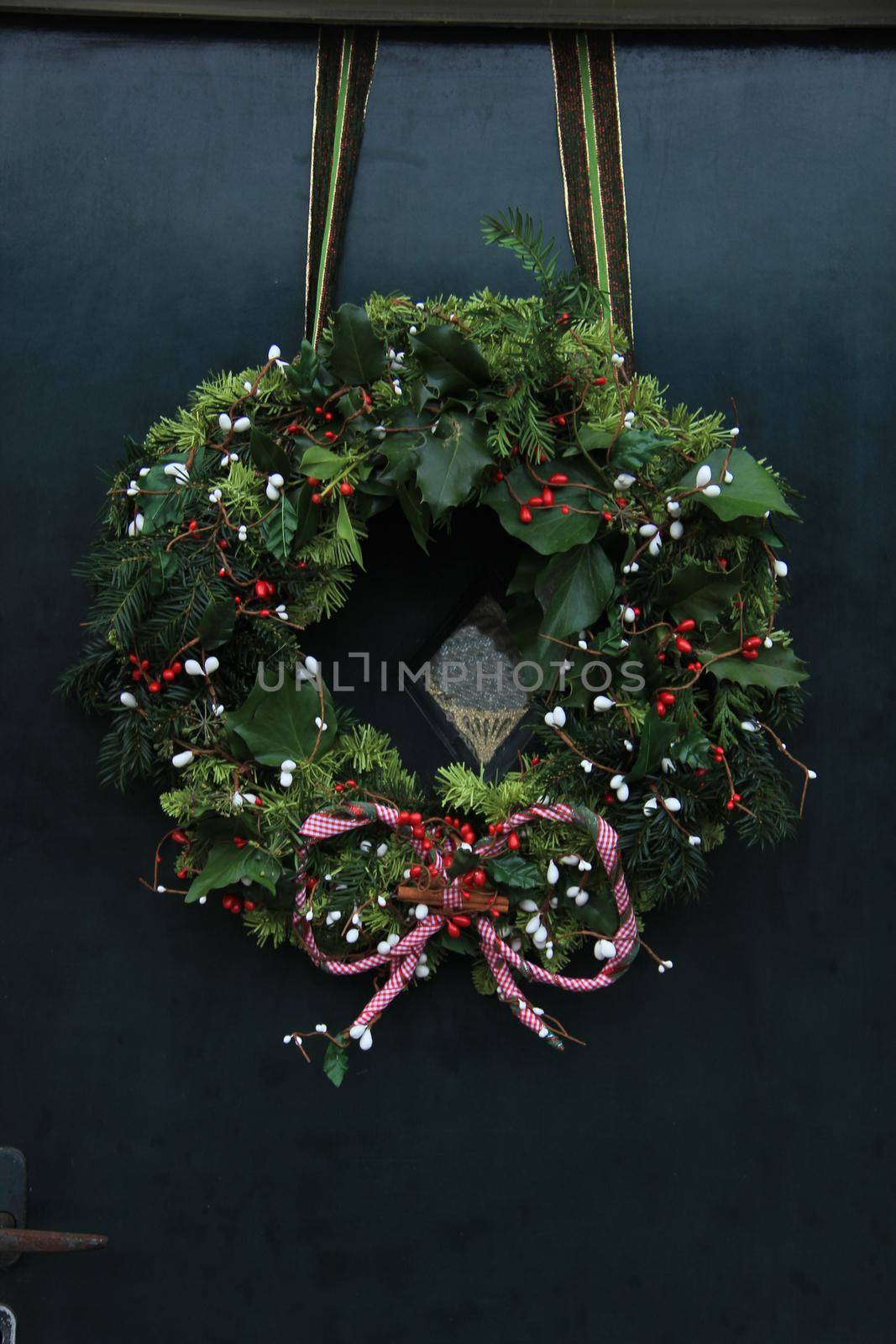 Classic christmas wreath with decorations on a door by studioportosabbia