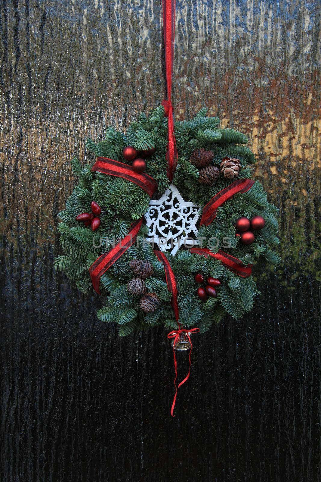 Classic christmas wreath with decorations on a door by studioportosabbia