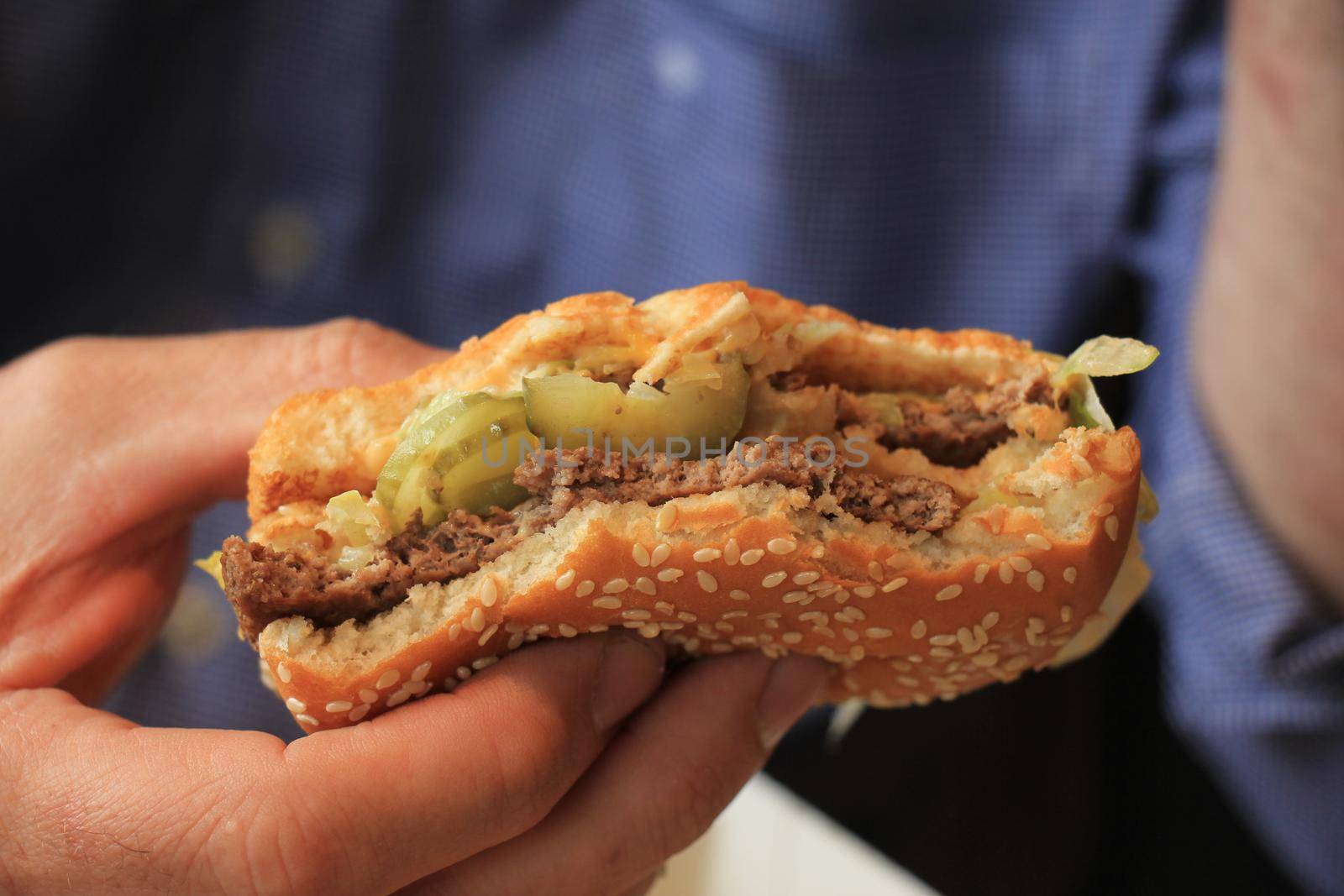 Man holding a fresh made hamburger by studioportosabbia