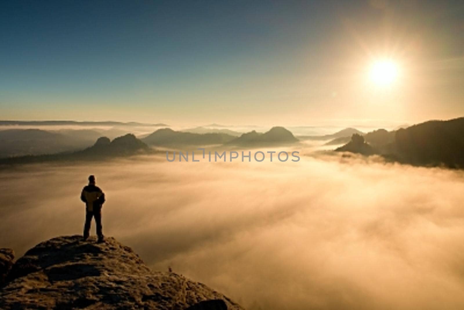 Man stands on peak of sandstone rock in Saxony Switzerland park and watching to Sun. Beautiful miracle of nature by rdonar2