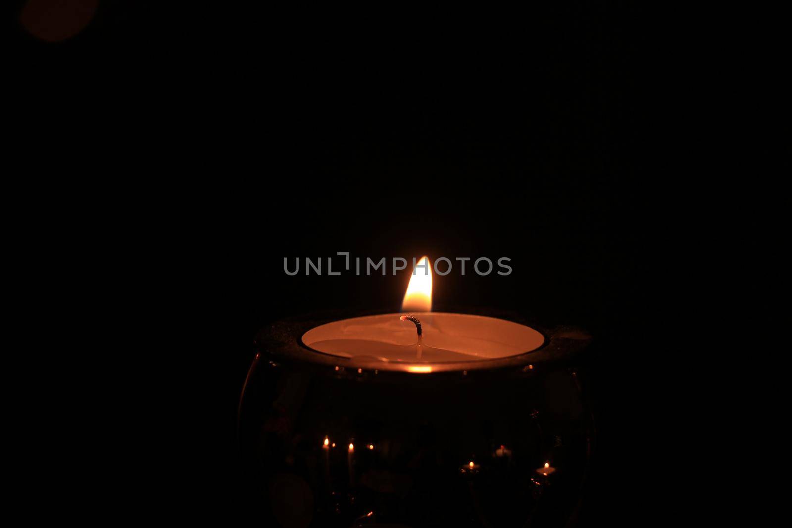Single burning candle, close-up in the dark by studioportosabbia