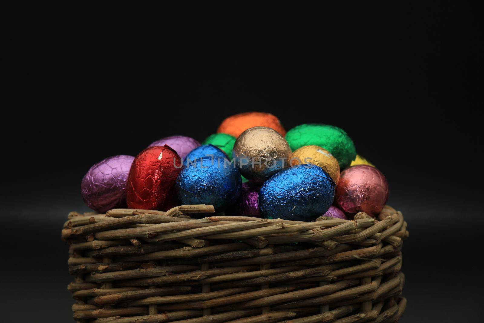 Foil wrapped chocolate easter eggs in a wicker basket