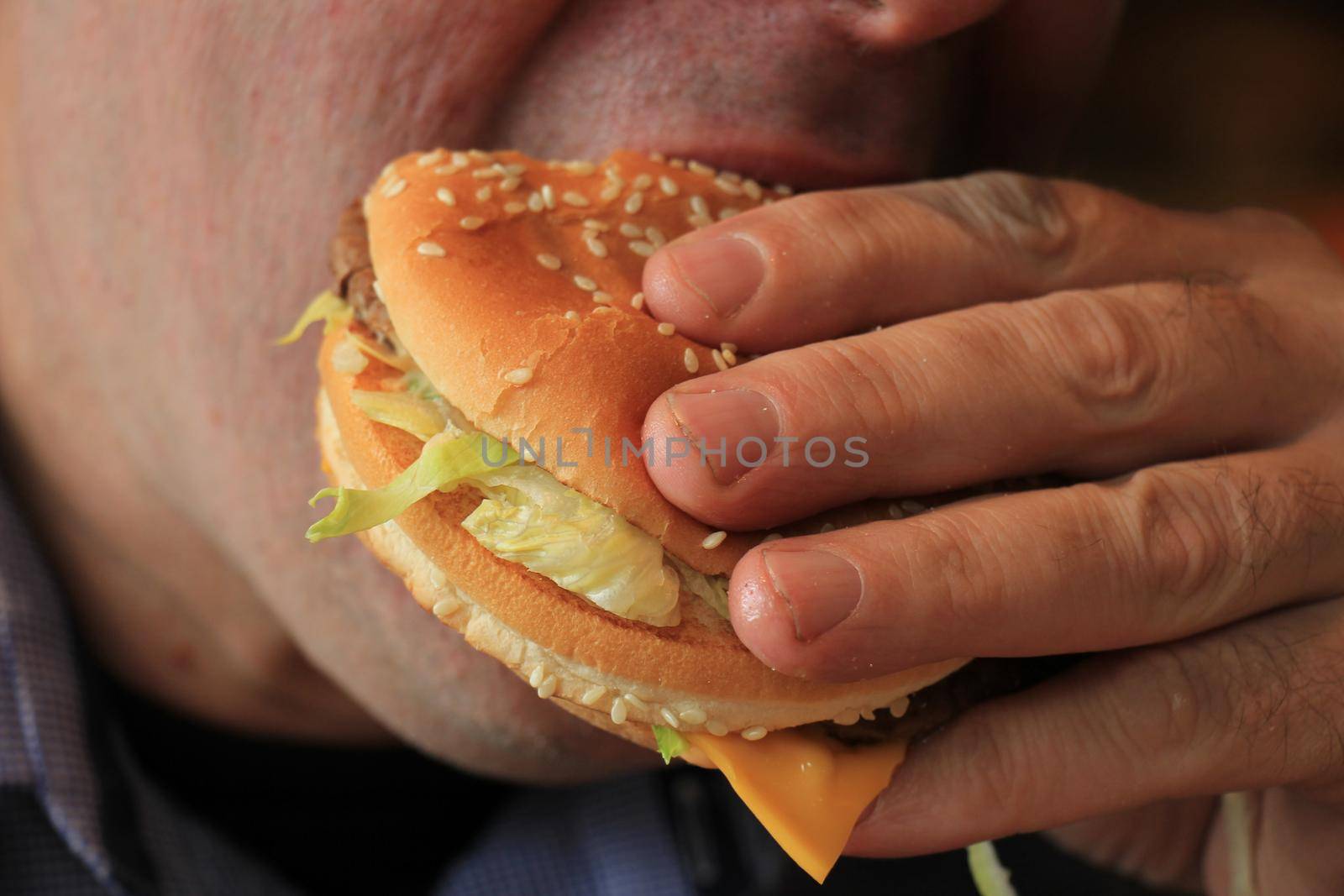 Man eating a fresh made hamburger by studioportosabbia
