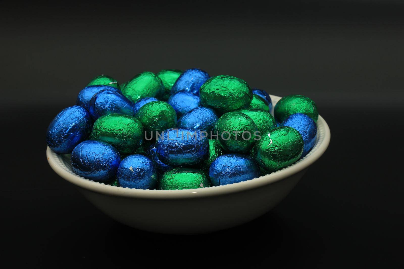 Foil wrapped chocolate easter eggs in a white porcelain bowl