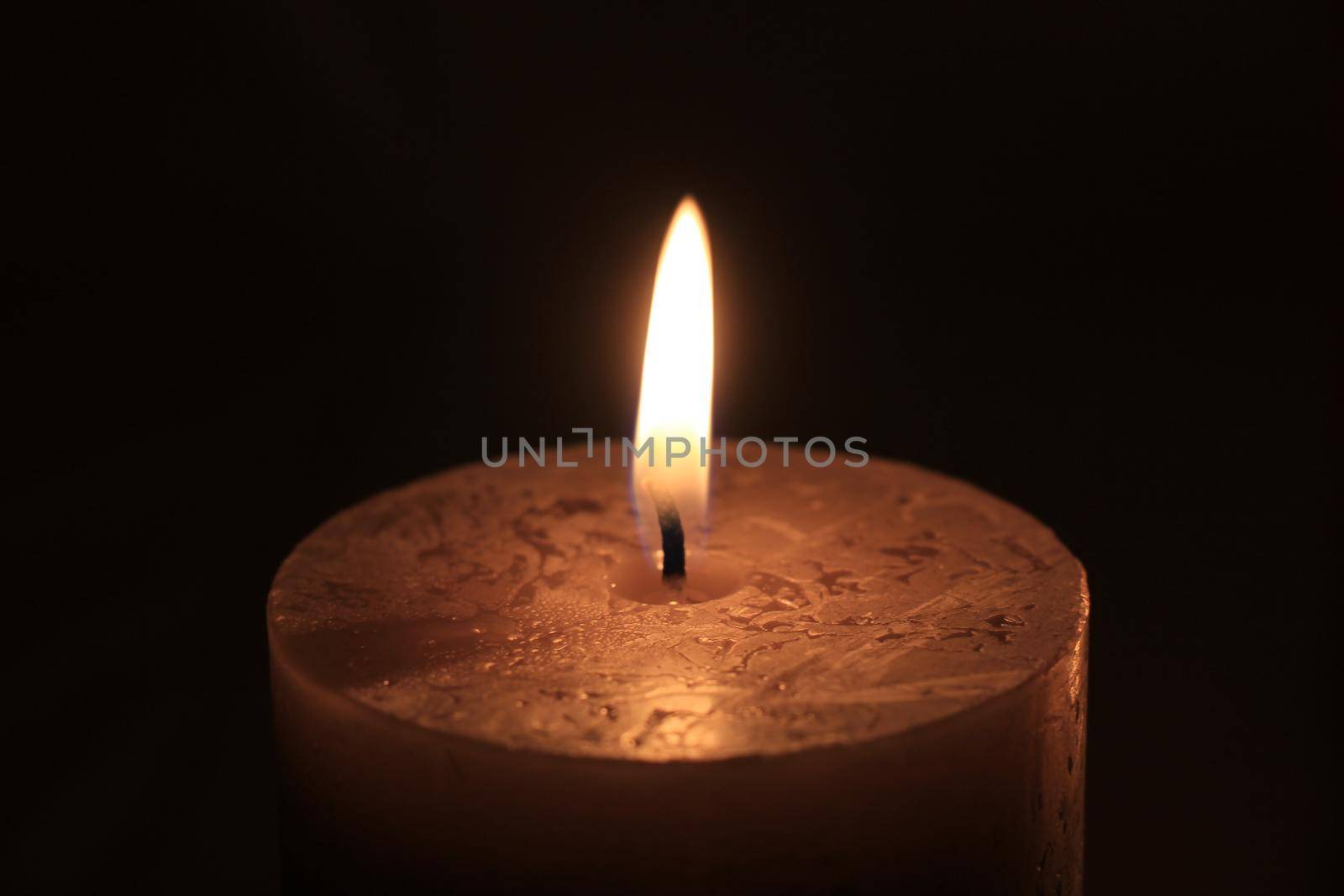 Closeup of a big burning candle , dark color by studioportosabbia
