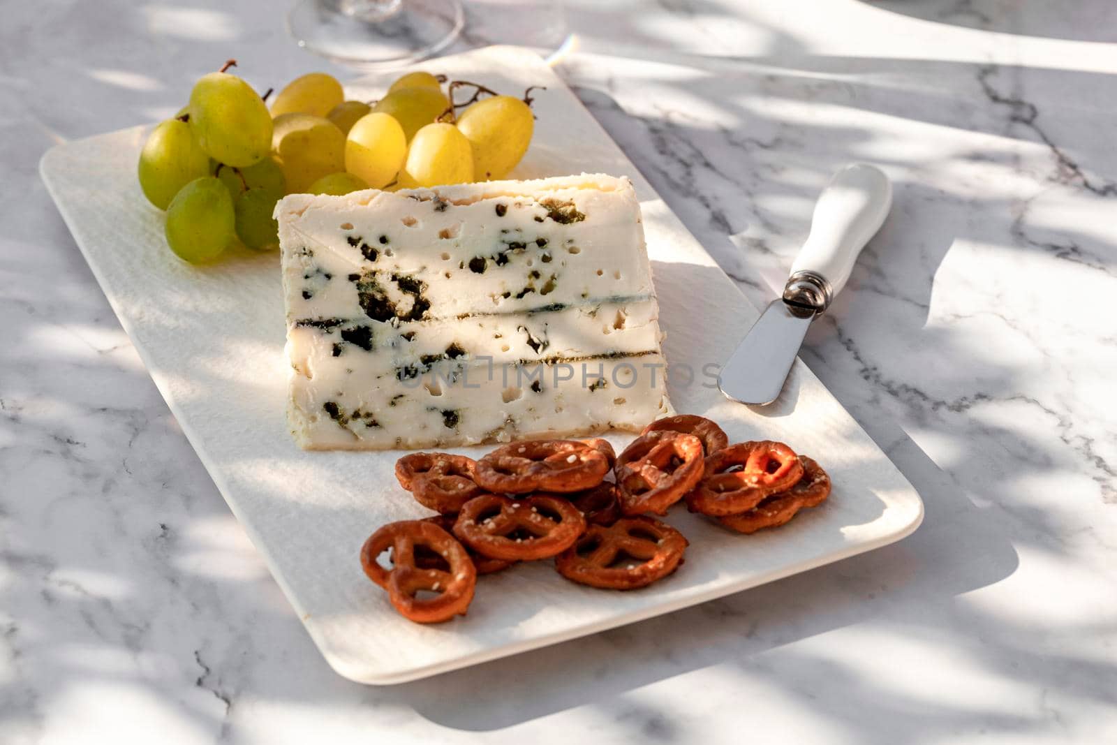 gorgonzola cheese served with green grapes and snacks outdoors, hard light