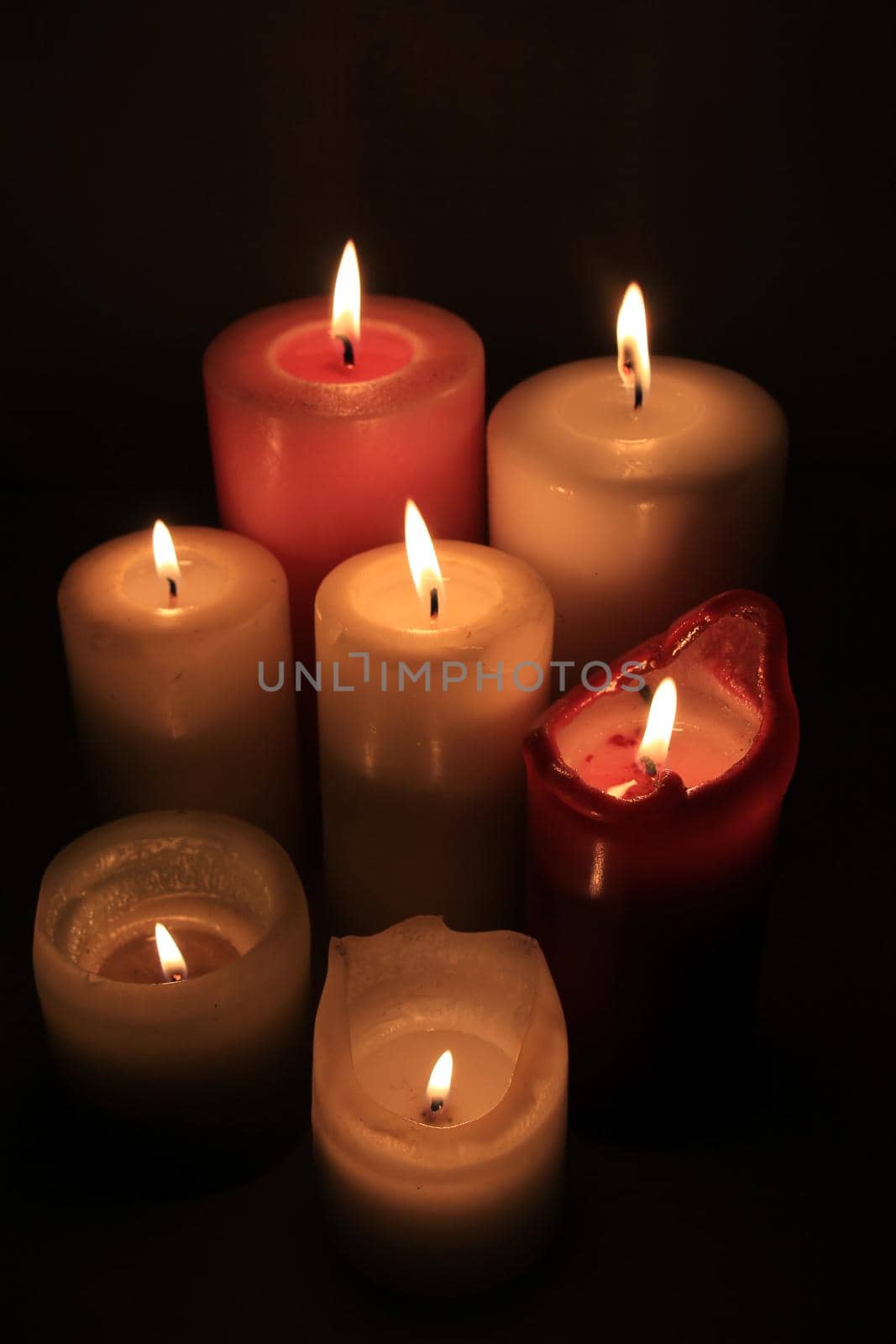 Group of burning candles in different heights and colors