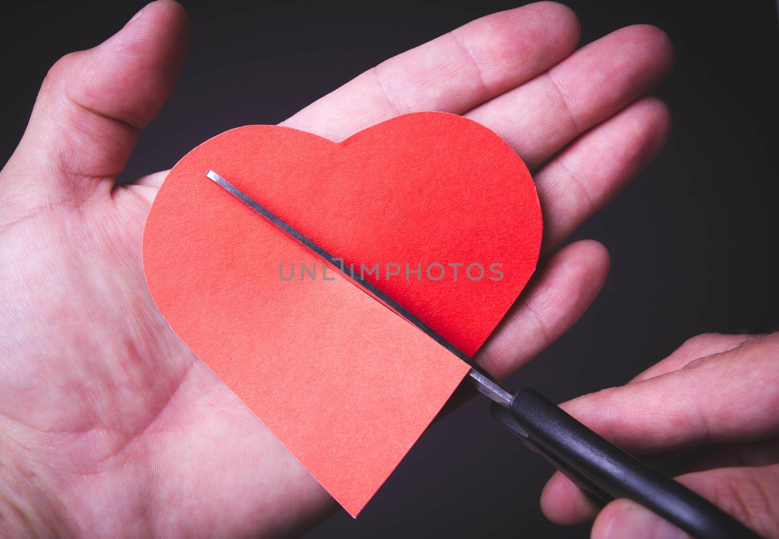 Broken heart. Divorce of a married couple. Broken marriage. Heart in hand and scissors.