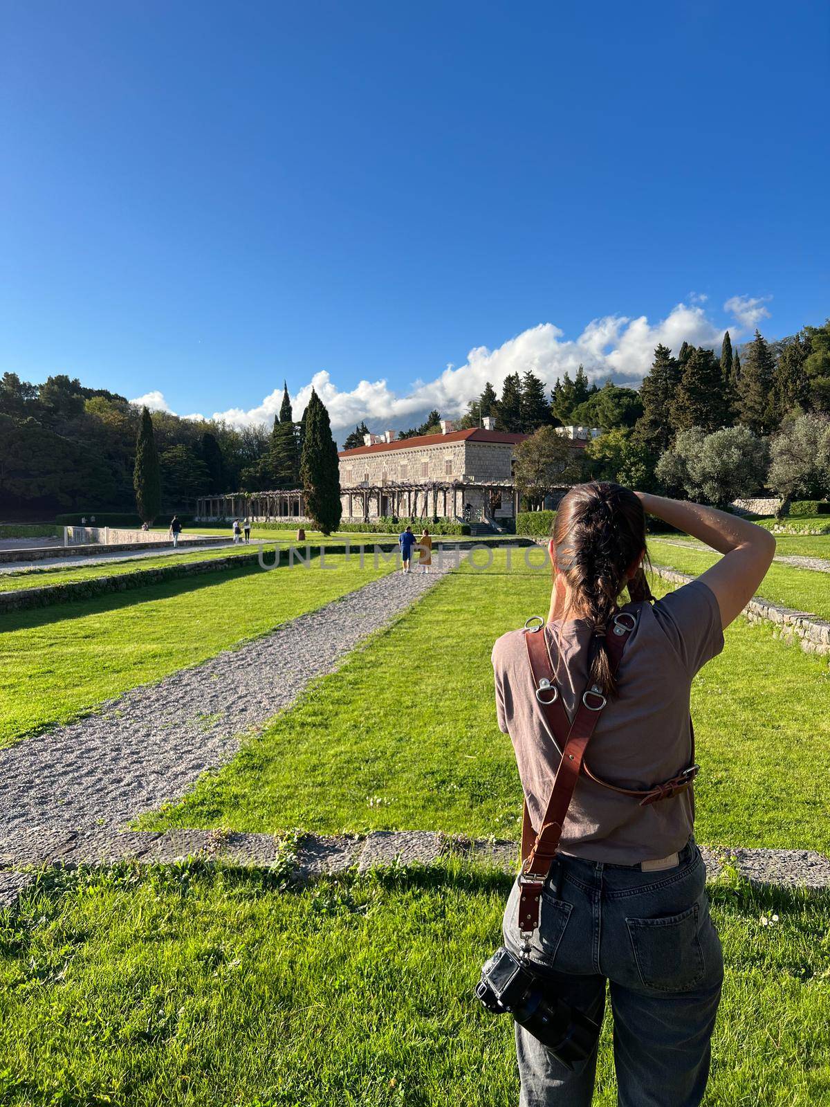 Girl photographs the garden of Villa Milocer. Back view. High quality photo