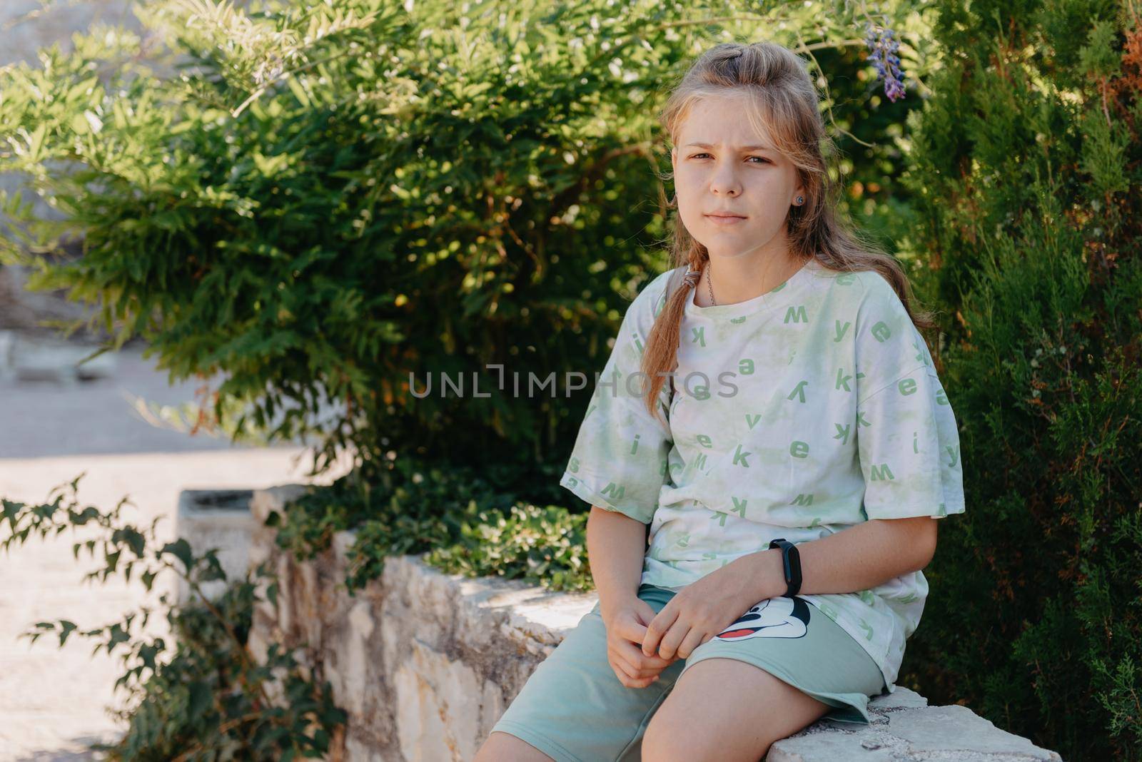 Girl tourist walking through ancient narrow street on a beautiful summer day in MEDITERRANEAN MEDIEVAL CITY , OLD TOWN bUDVA, MONTENEGRO. Young beautiful cheerful woman walking on old street at tropical town. Pretty girl looking at you and smiling