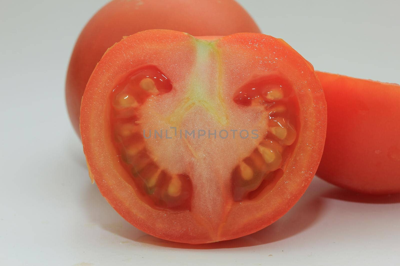 Fresh tomato, cut in half, in closeup by studioportosabbia