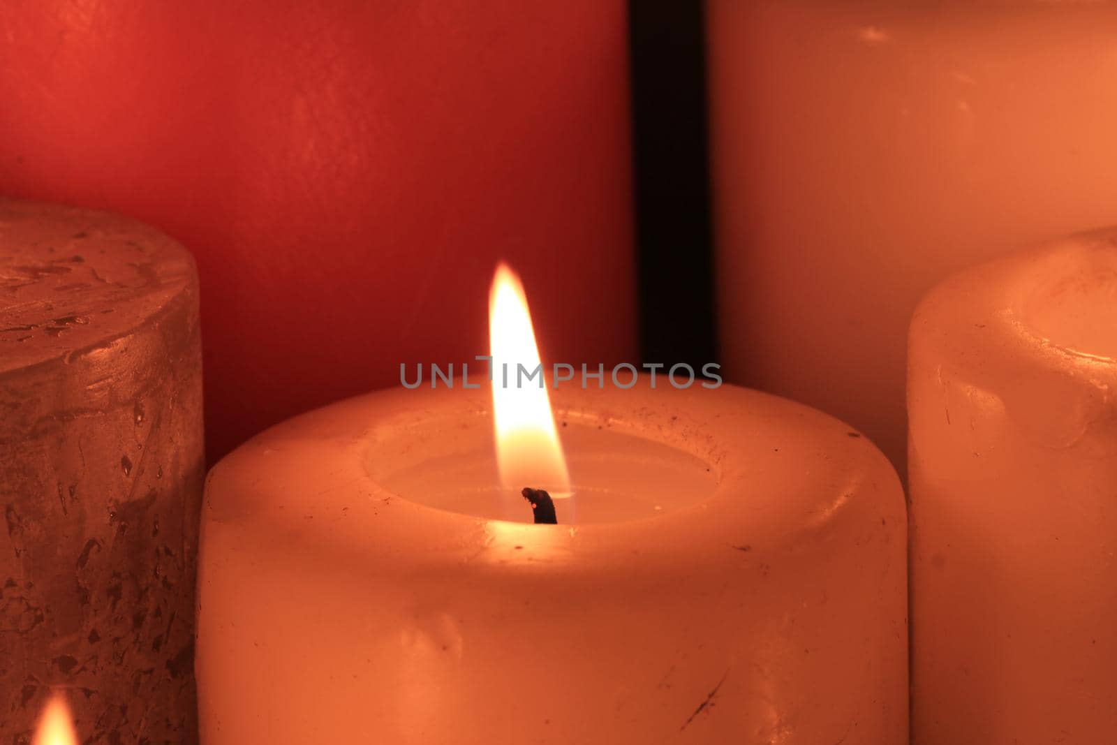 Closeup of a big burning candle , ivory color by studioportosabbia