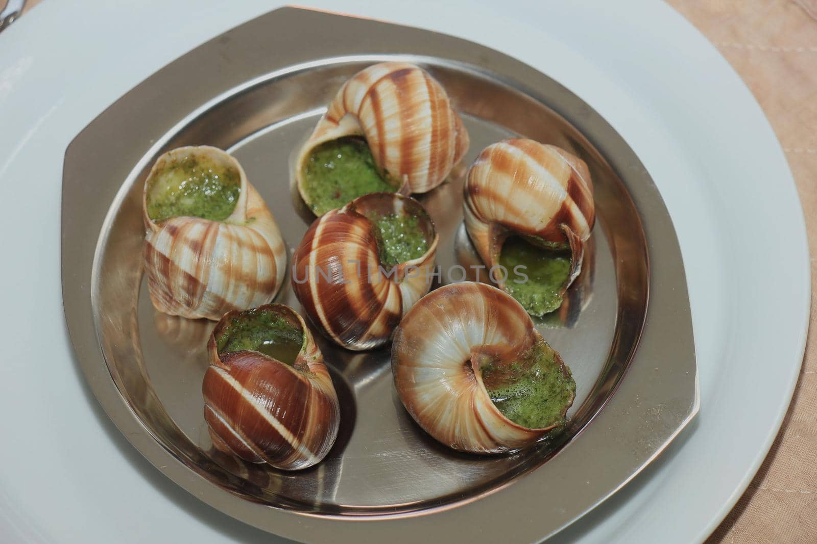 Escargots de Bourgogne on a metal plate, just out of the oven by studioportosabbia