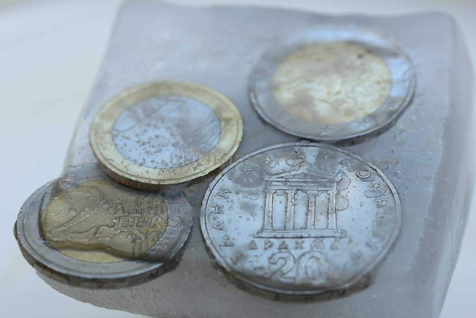 Frozen Assets: Greek euro and Drachme coins in ice