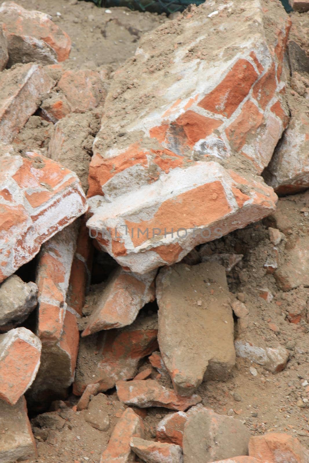 Pile of broken red bricks on construction site by studioportosabbia