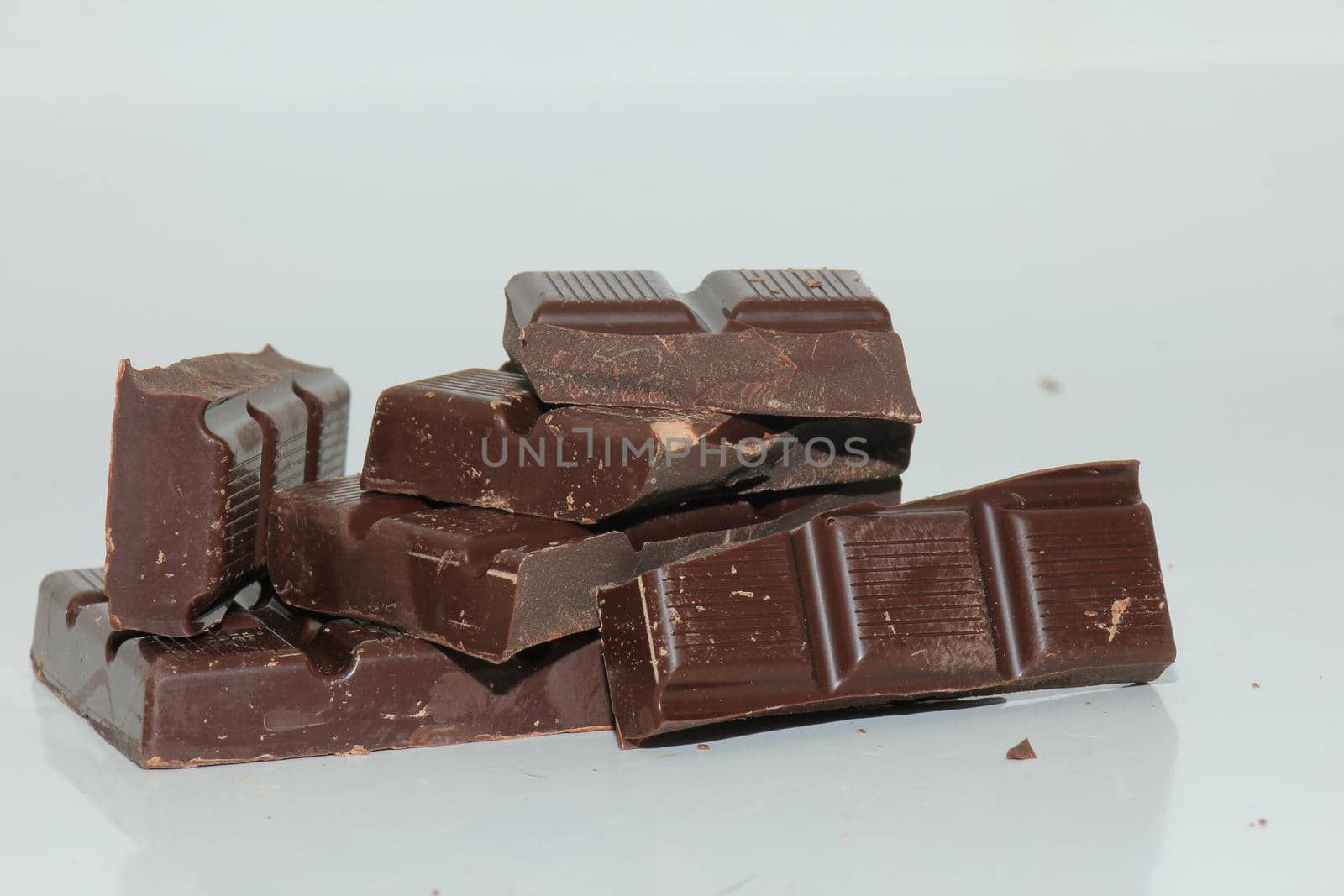 Dark chocolate bar , broken in oneven pieces by studioportosabbia