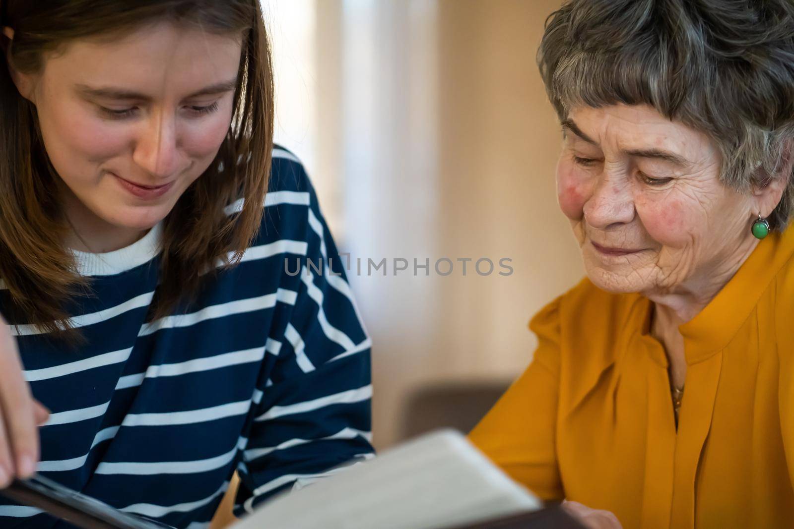 Grandmother and her young granddaughter spent great time together, family members look at photos from the youth of an elderly parent, through the pages of the album and recall funny stories from life.
