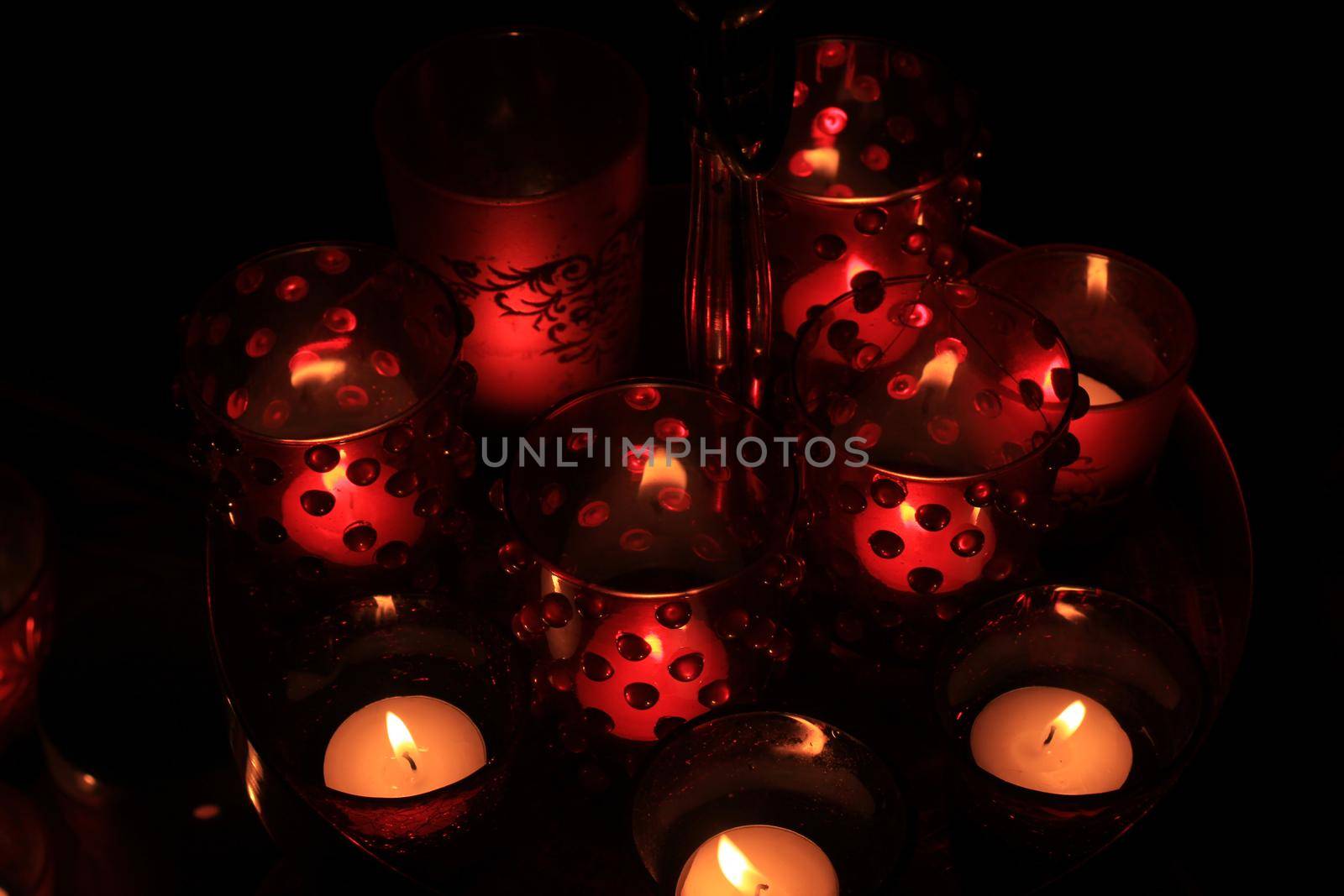 Red candles and votive lights burning in a christmas arrangement by studioportosabbia