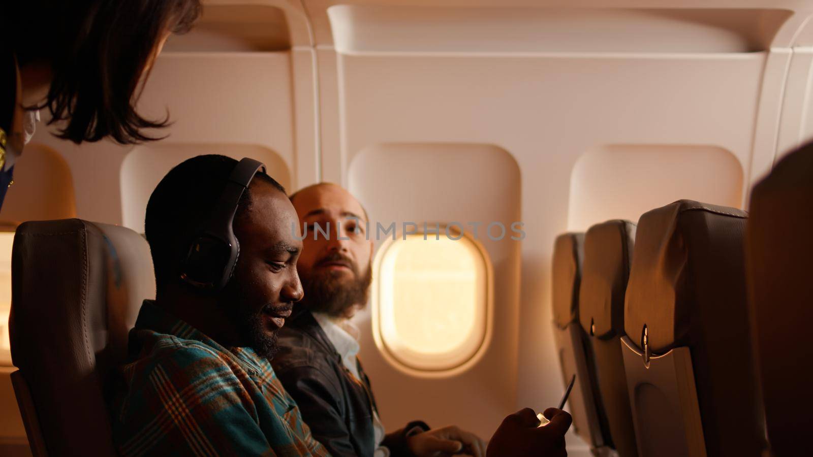 Male passenger talking to flight attendant on airplane by DCStudio