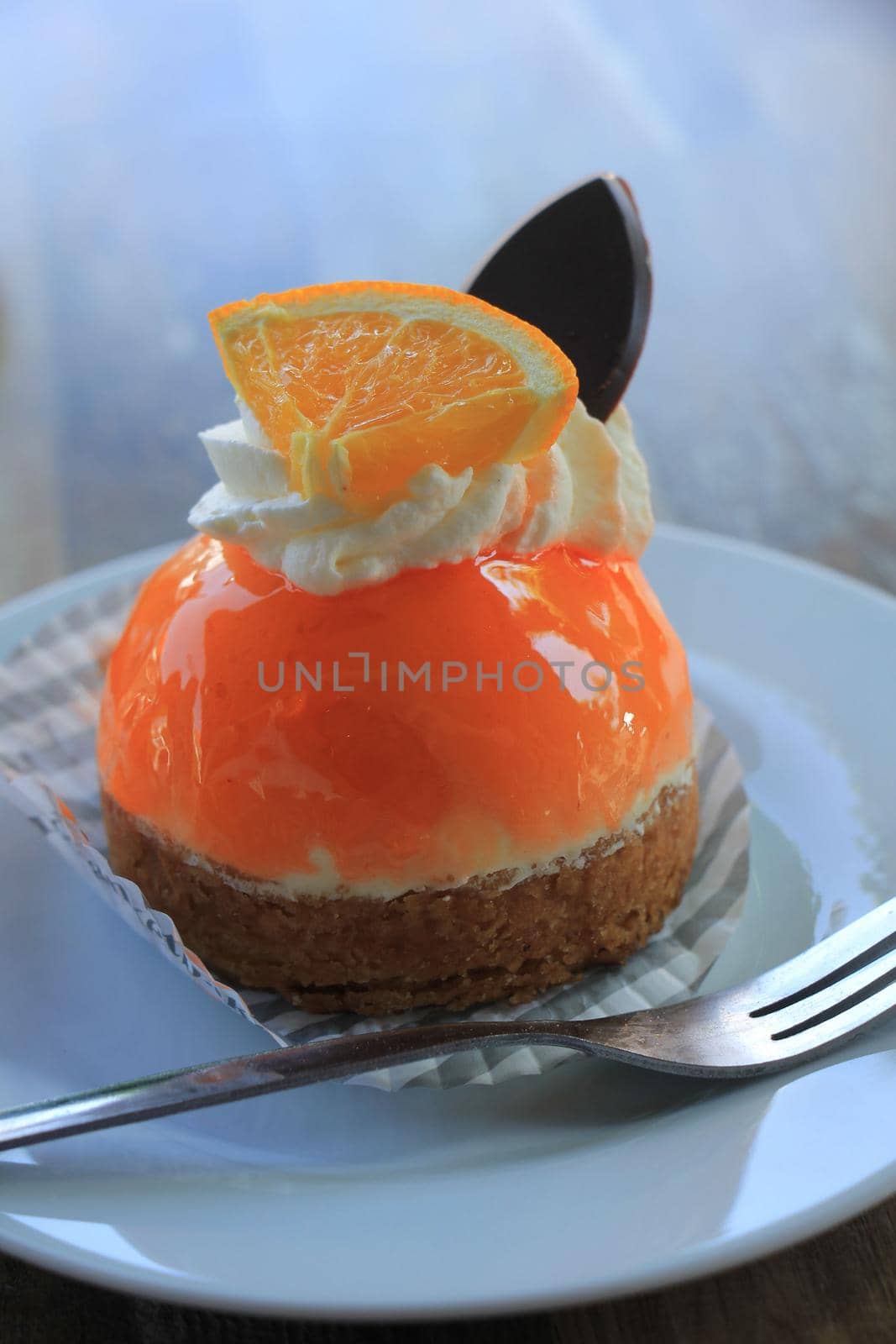 Fresh orange mousse confectionery, with cream and a chocolate decoration by studioportosabbia