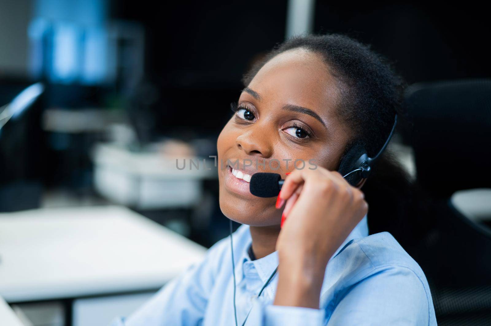 African young woman talking to a client on a headset. Female employee of the call center