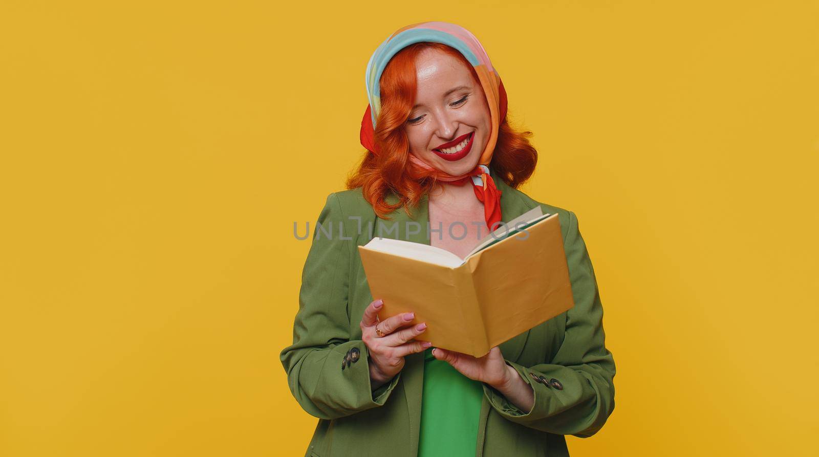 Redhead young woman reading funny interesting fairytale story book, leisure hobby, knowledge wisdom, education, learning, study, wow. Red hair ginger girl isolated alone on yellow studio background