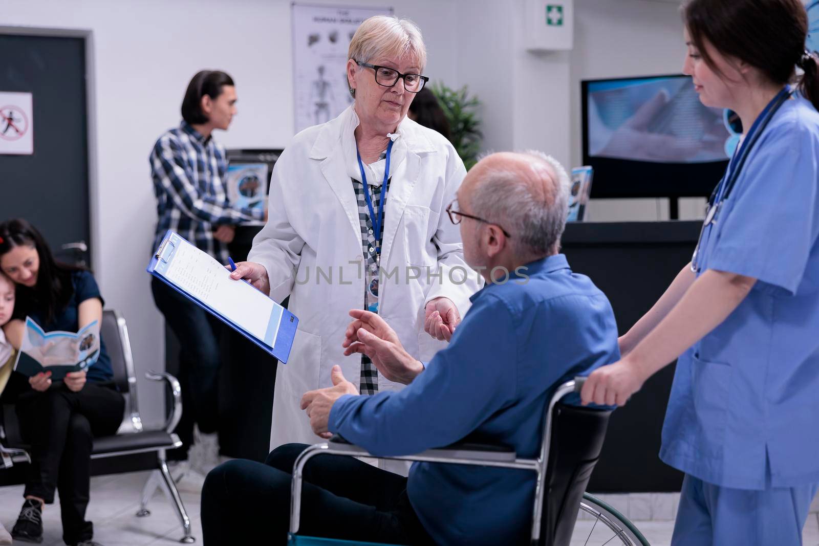 Senior doctor talking with retired person using wheelchair about appointment by DCStudio