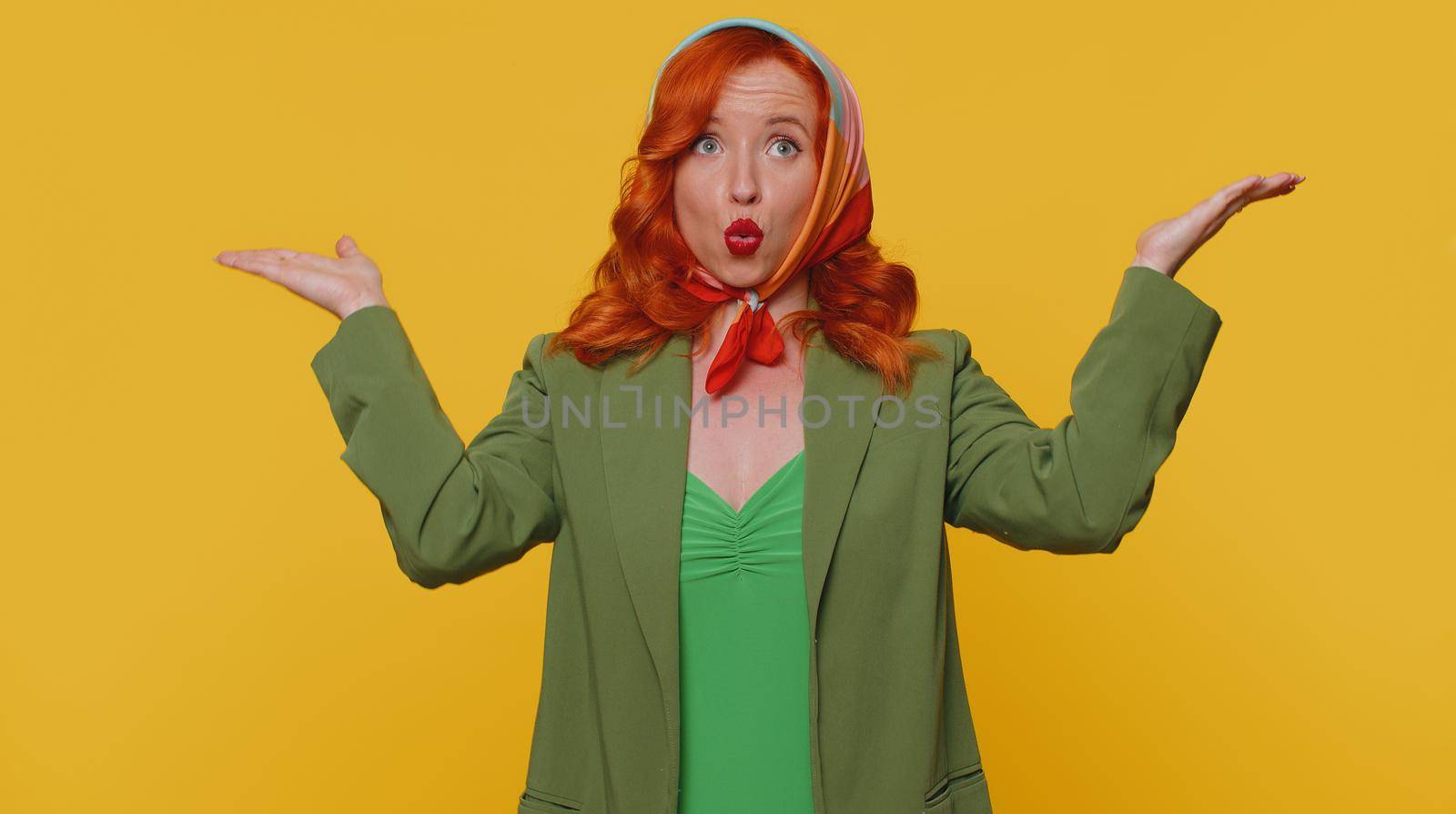 Excited amazed ginger woman in green jacket touching head, showing explosion, looking worried and shocked, professional burnout. Looking surprised wow girl isolated alone on yellow studio background