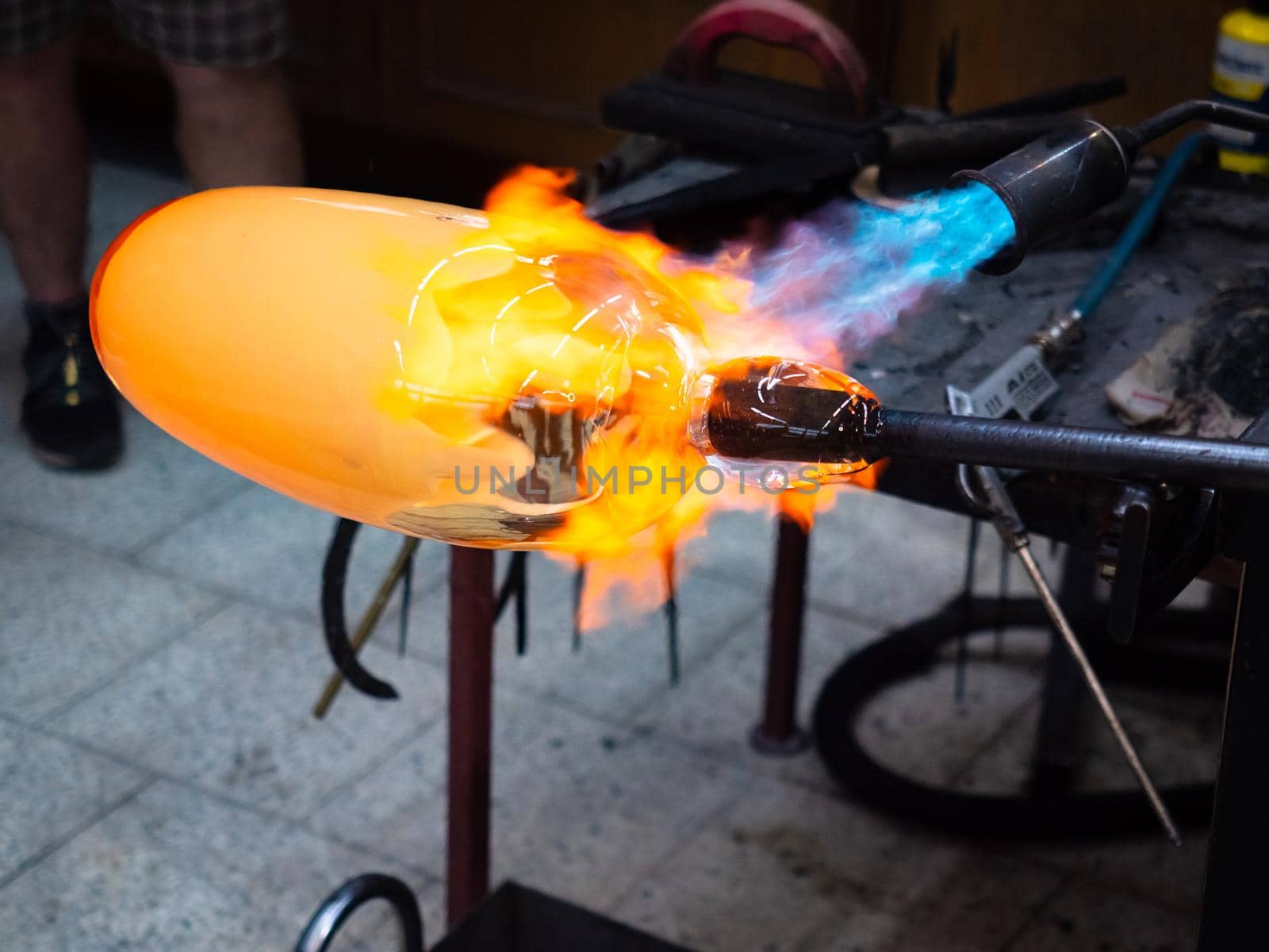 Artist glass blowing process. The glassblower master with co-workers are creating an amazing piece of art from molten glass