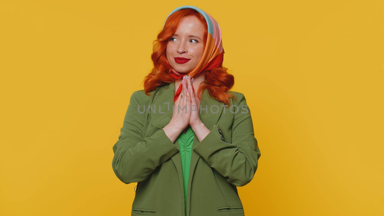 Sneaky cunning woman with tricky face gesticulating and scheming evil plan, thinking over devious villain idea, cunning cheats, jokes and pranks. Redhead girl on yellow studio background alone indoors