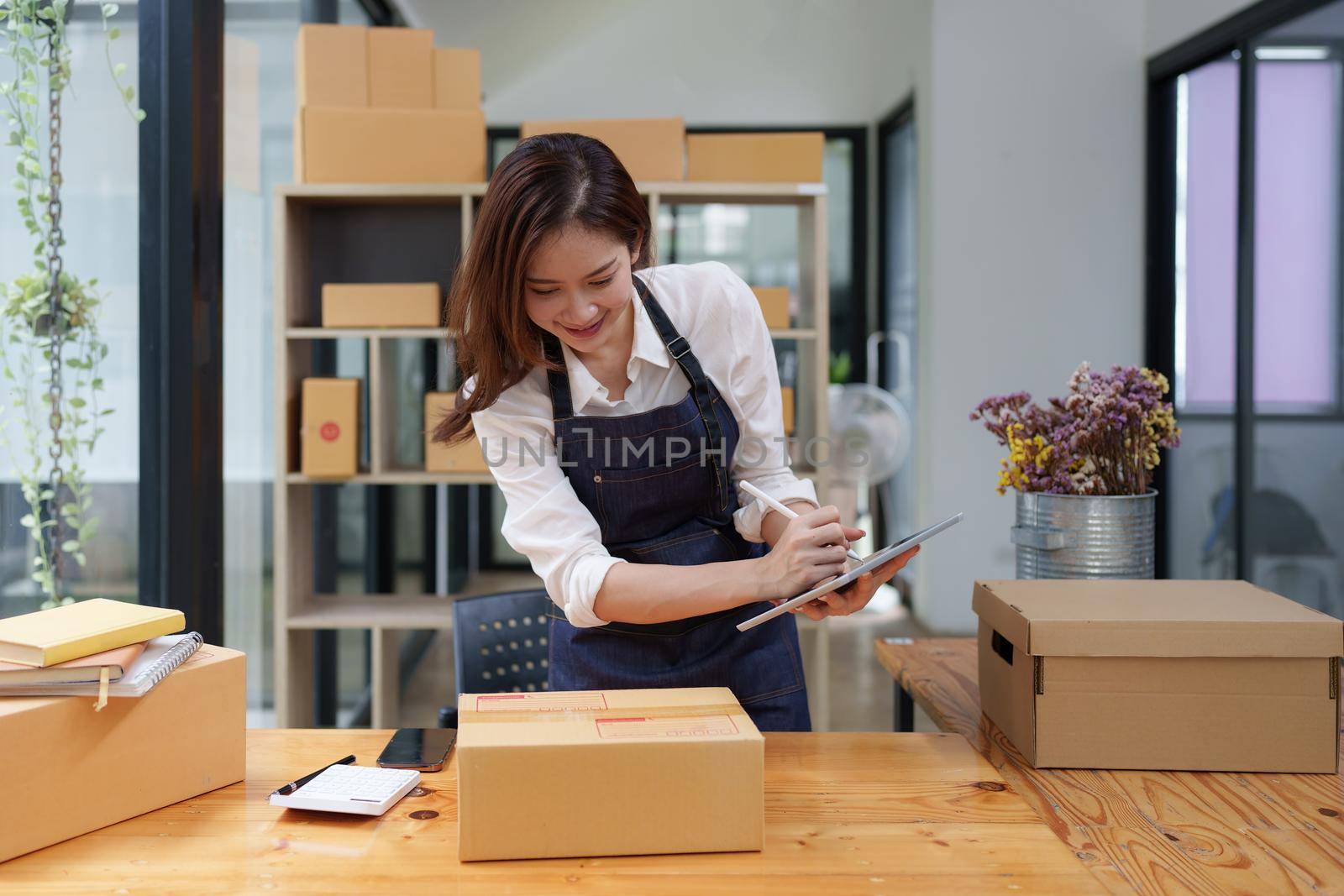 Attractive Asian entrepreneur business woman checking order by tablet by itchaznong